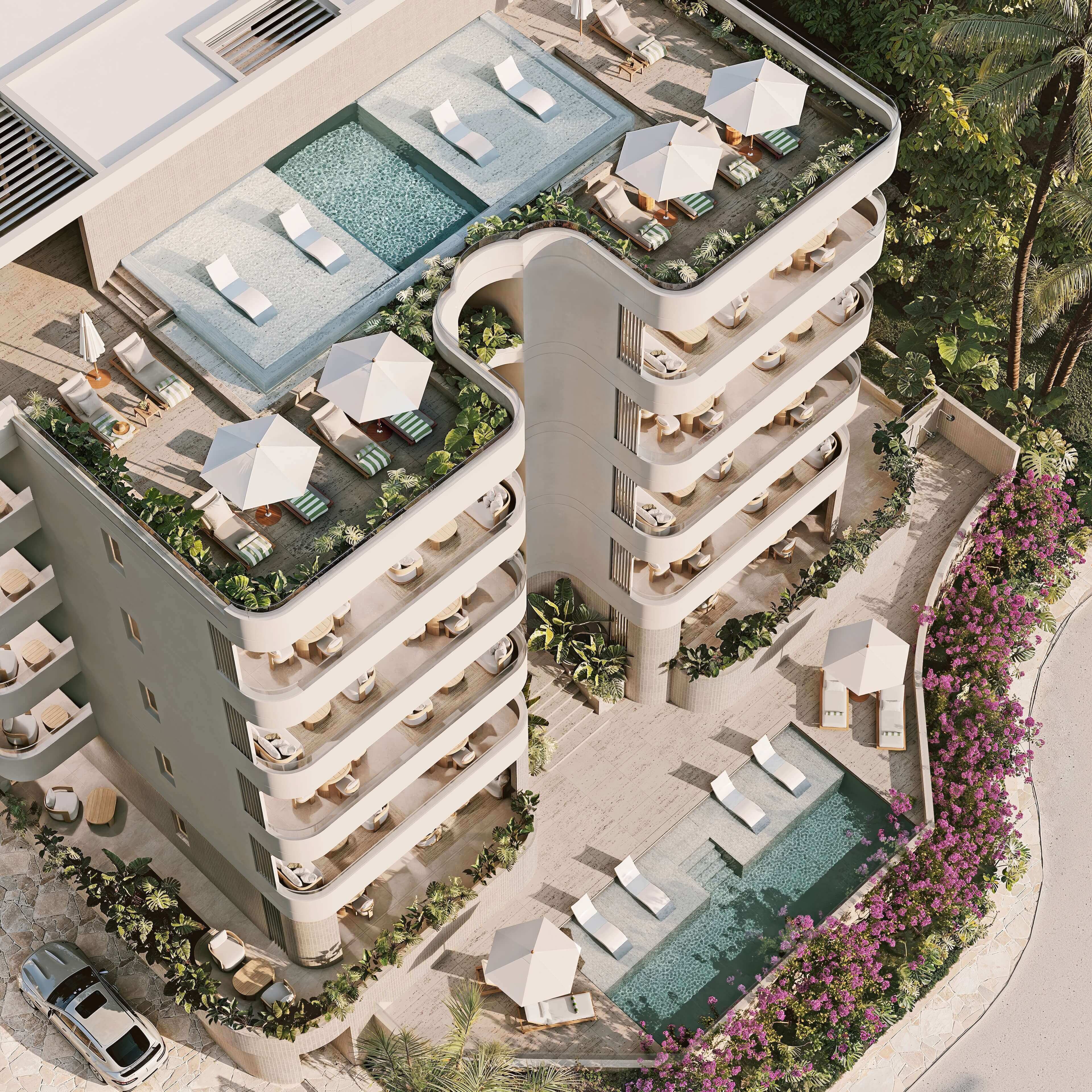 Aerial view of a modern building with rooftop pools and a landscaped courtyard.