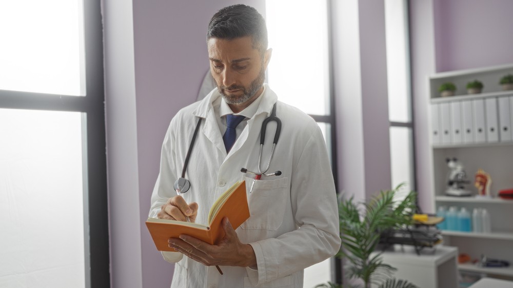 Médecin prenant des notes dans un bureau, symbolisant l'importance de l'assurance vie pour les personnes ayant des antécédents de cancer.