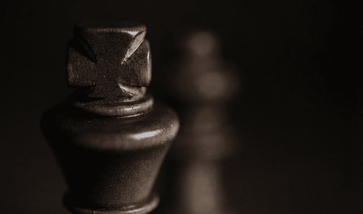 Close-up of a dark wooden chess piece against a blurred background.