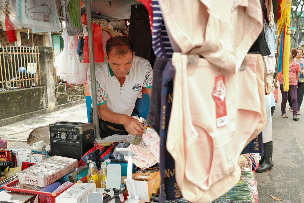 A man standing in front of a store selling items