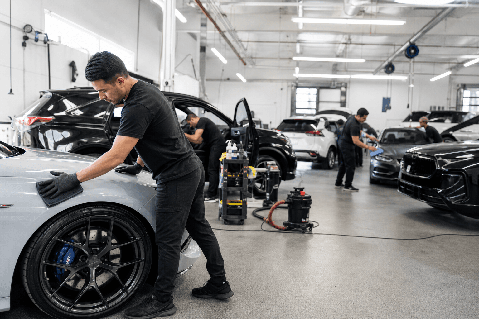 Busy detailing shop with a small team working on several customer cars