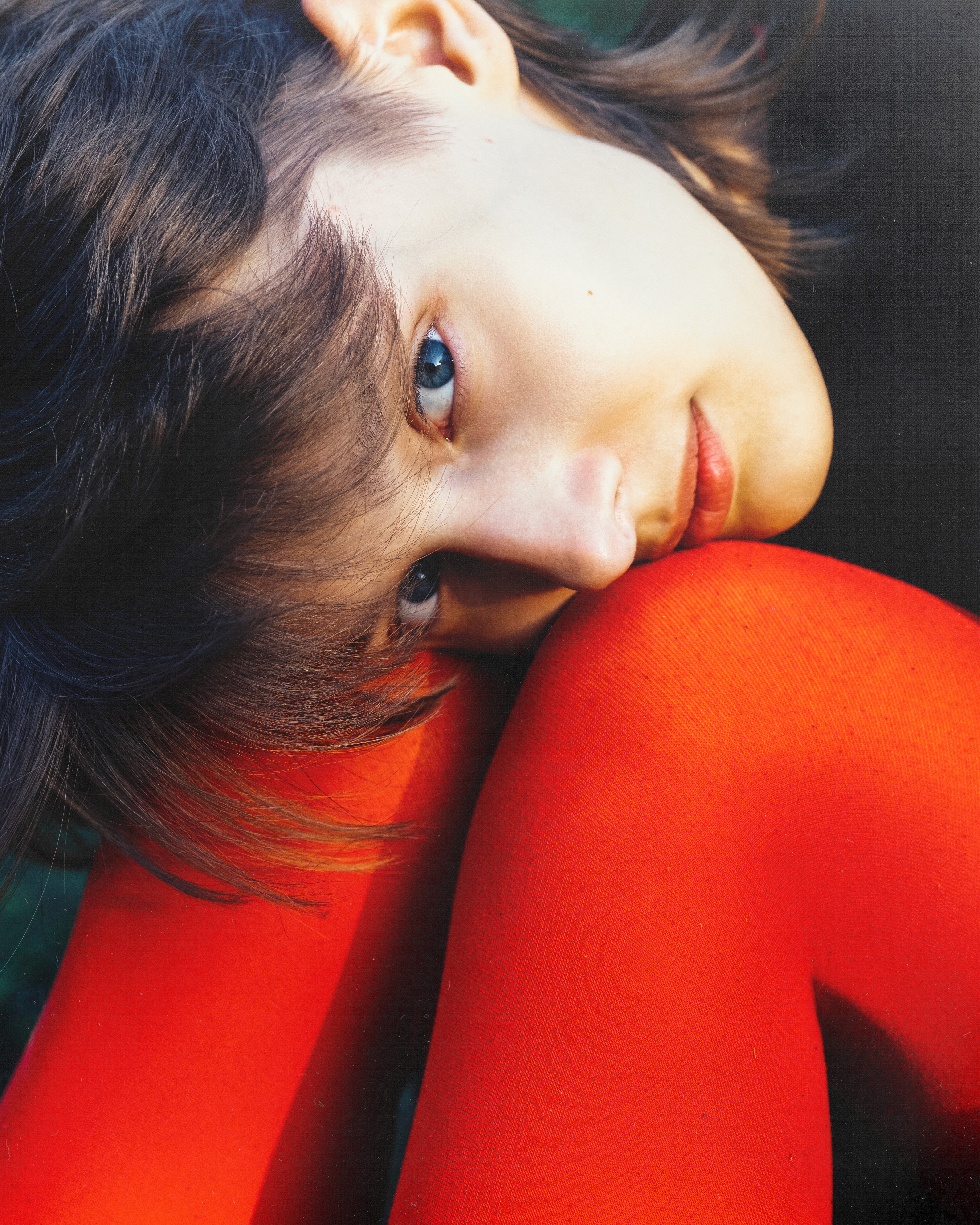 Ewa – Red Persona - close-up with her face resting on red tights.