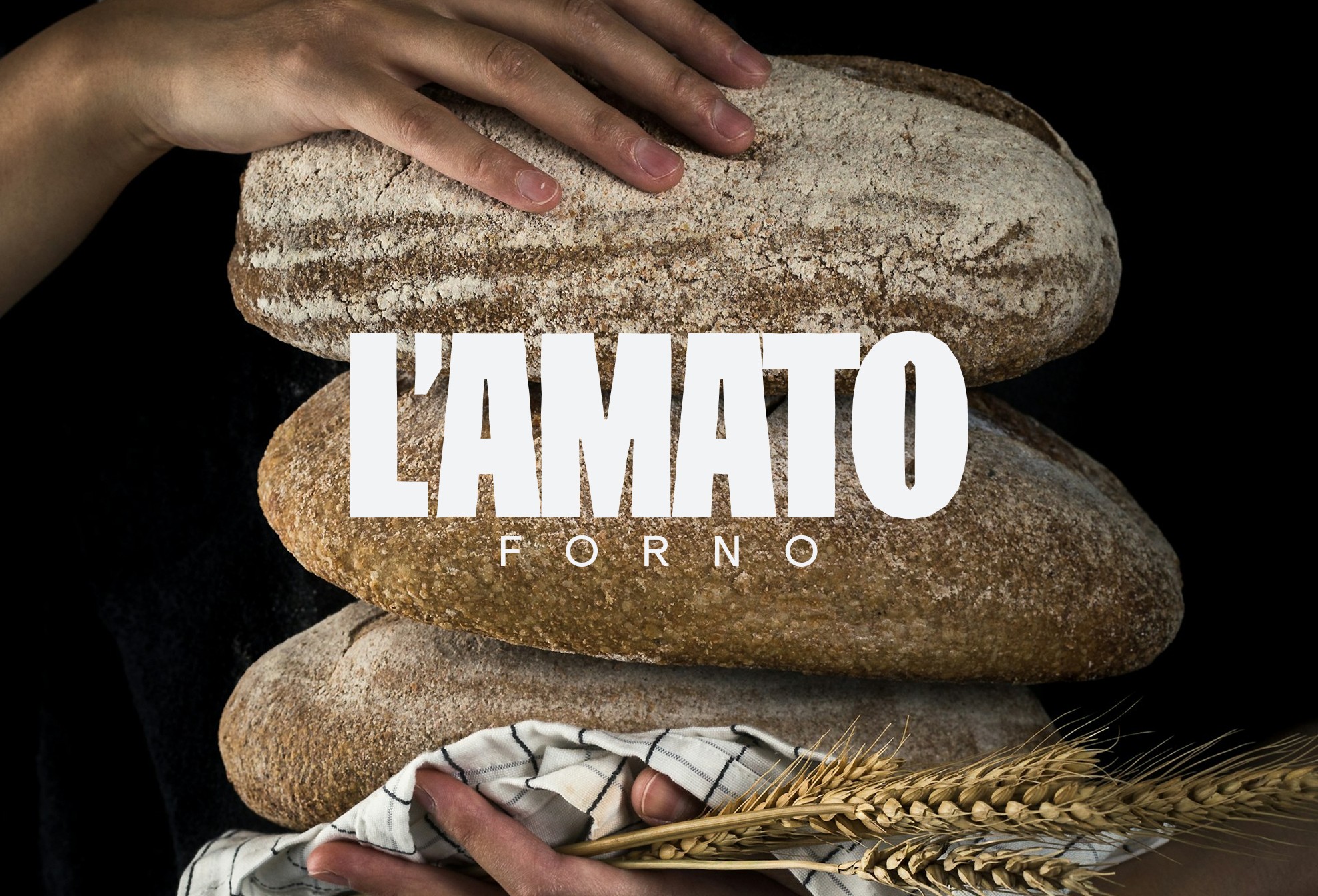 Pagnotte di pane artigianale impilate con logo L'Amato Forno, brand identity per panificio