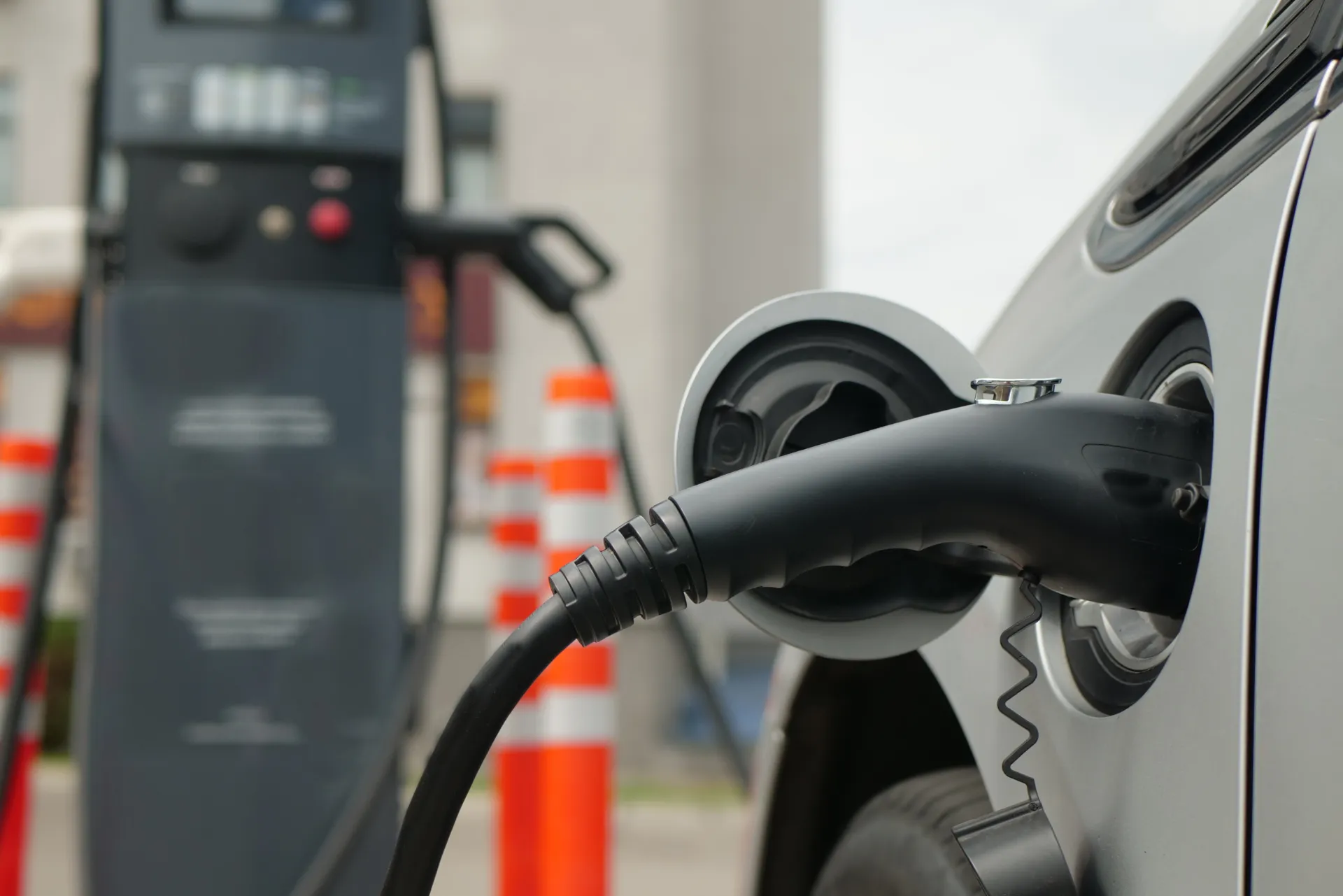 Weißes Elektroauto an der Ladestation. Elektroauto ist an der Station angeschlosse, da das Kabel in dem Auto steckt.