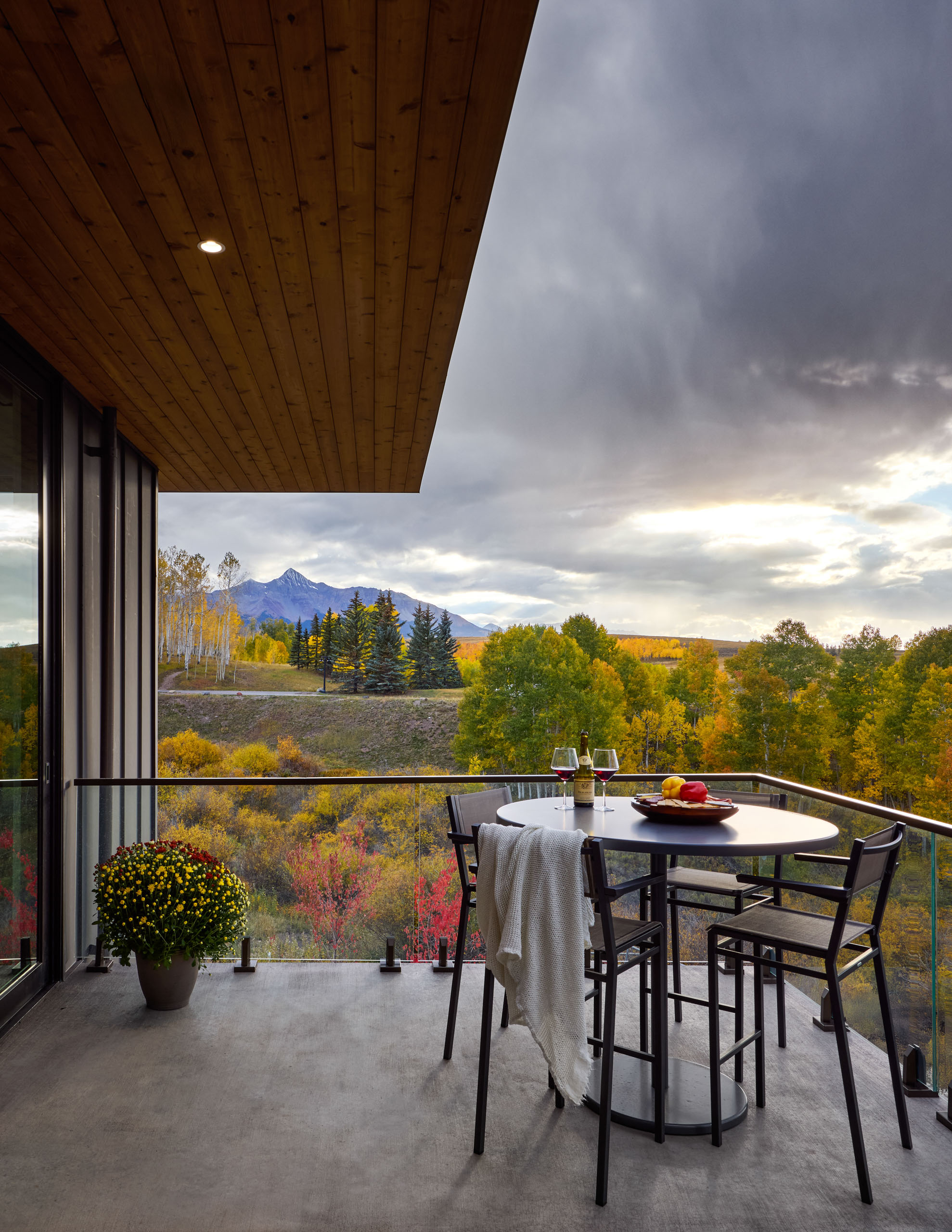 Balcony with table, chairs, and fall mountain view.