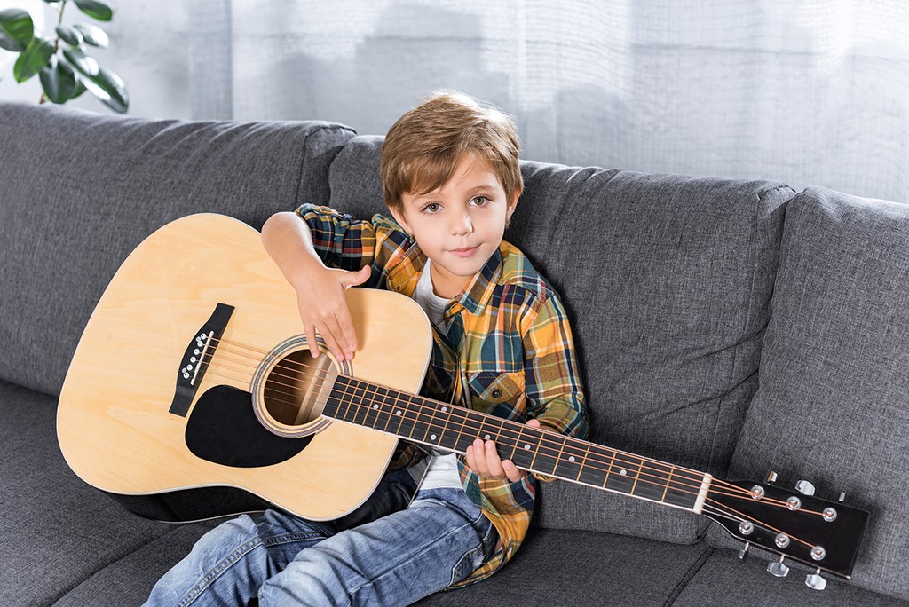 child on couch playing guitar