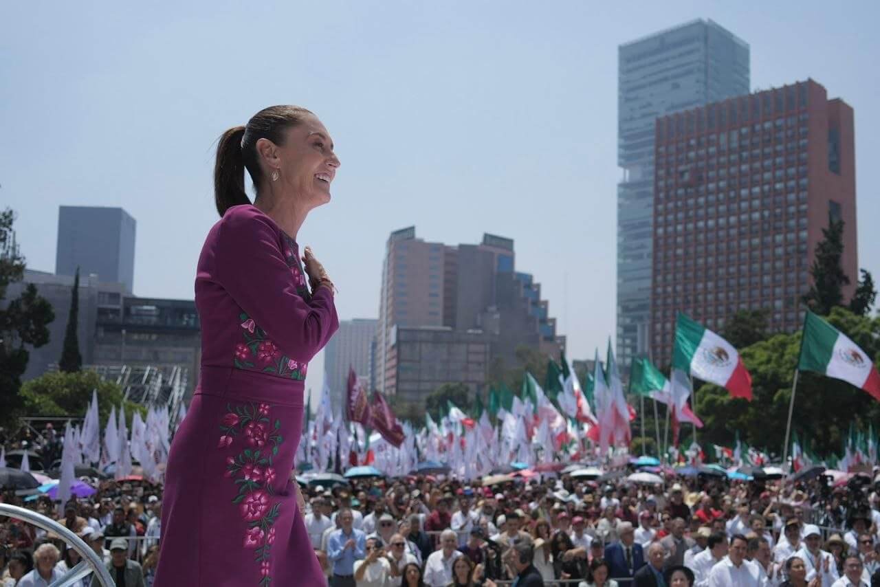 President Claudia Shienbaum stands before a large crowd in a city plaza.