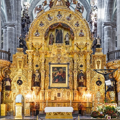 Isang maringal na altar ng simbahan na gawa sa ginto na may mga istatuwa at pagpipinta ng relihiyon, na napapaligiran ng mga haligi sa likuran.