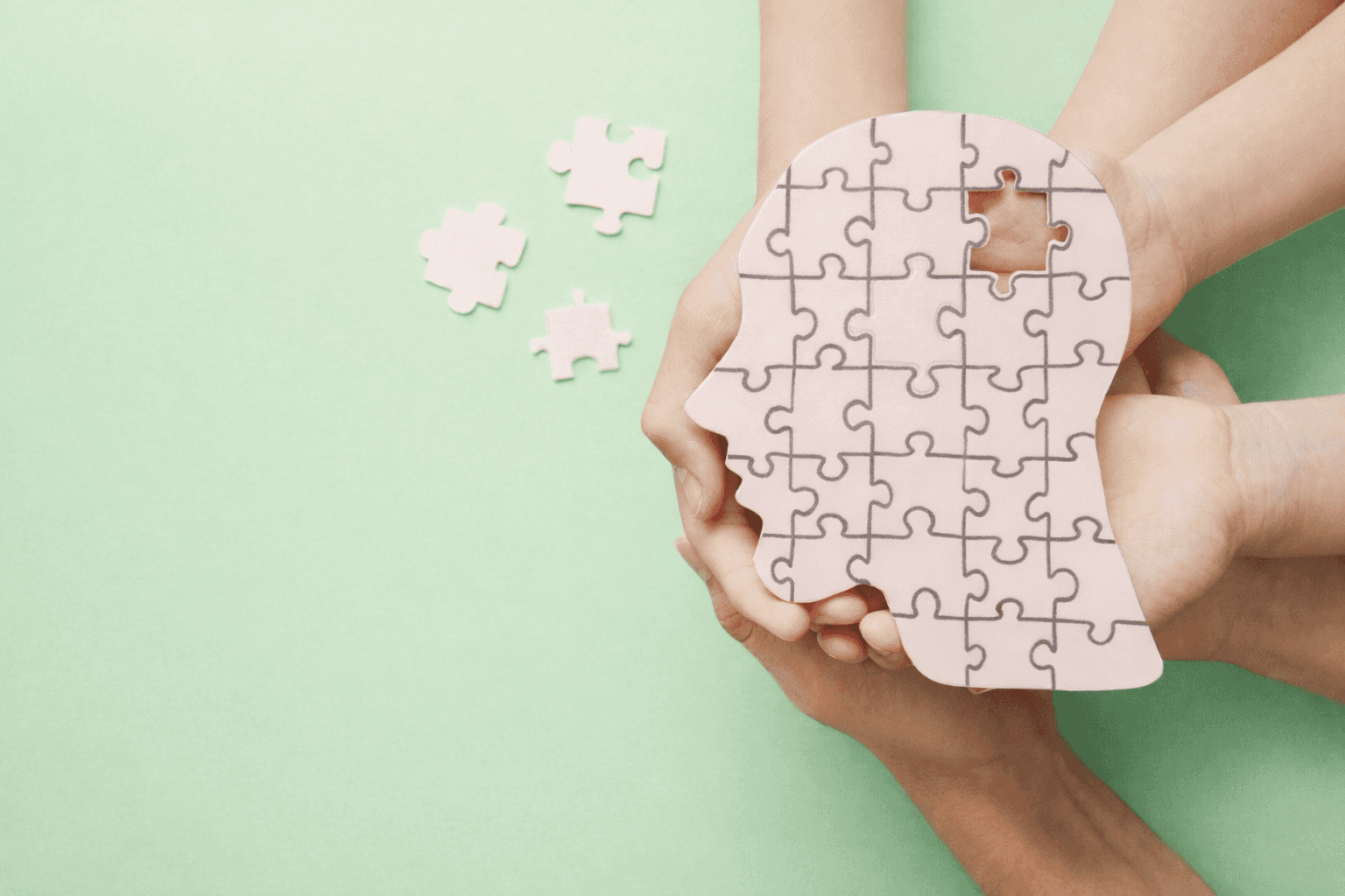 Puzzle-shaped human head held by hands with a missing piece, symbolising neurodiversity, communication, and cognitive support.