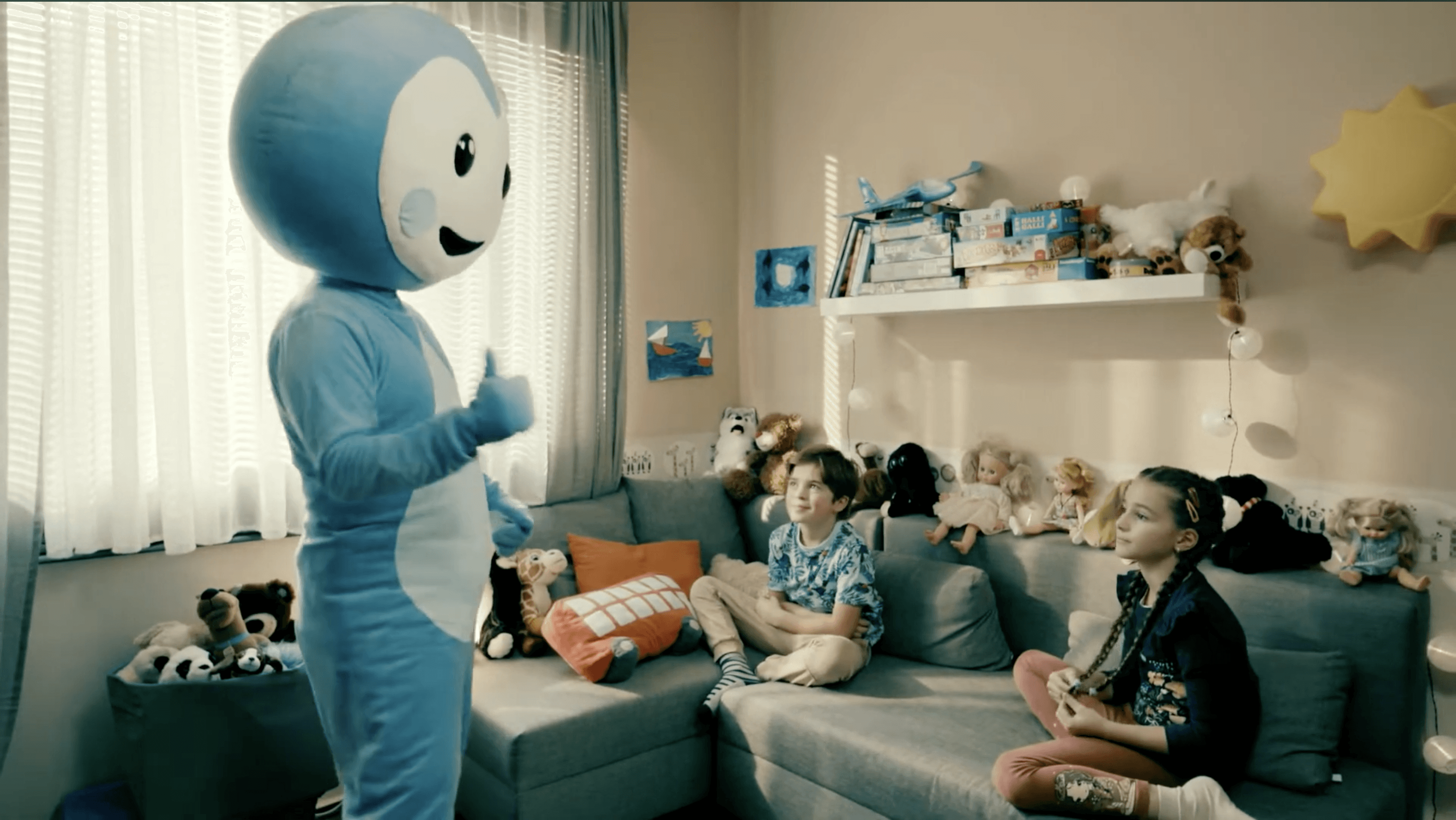 Cseppbarát kékl kabalafigurája beszélget a gyerekekkel a nappaliban.