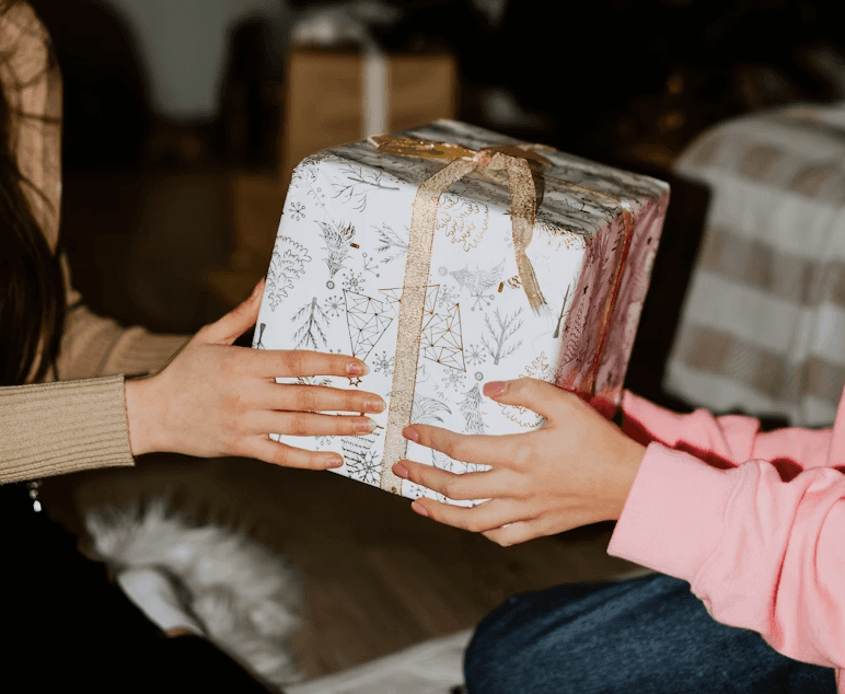 Two people passing a wrapped holiday gift between them during a white elephant exchange.