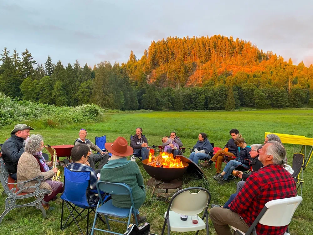 Community members gathered outdoors around a fire pit at Rooted Northwest.