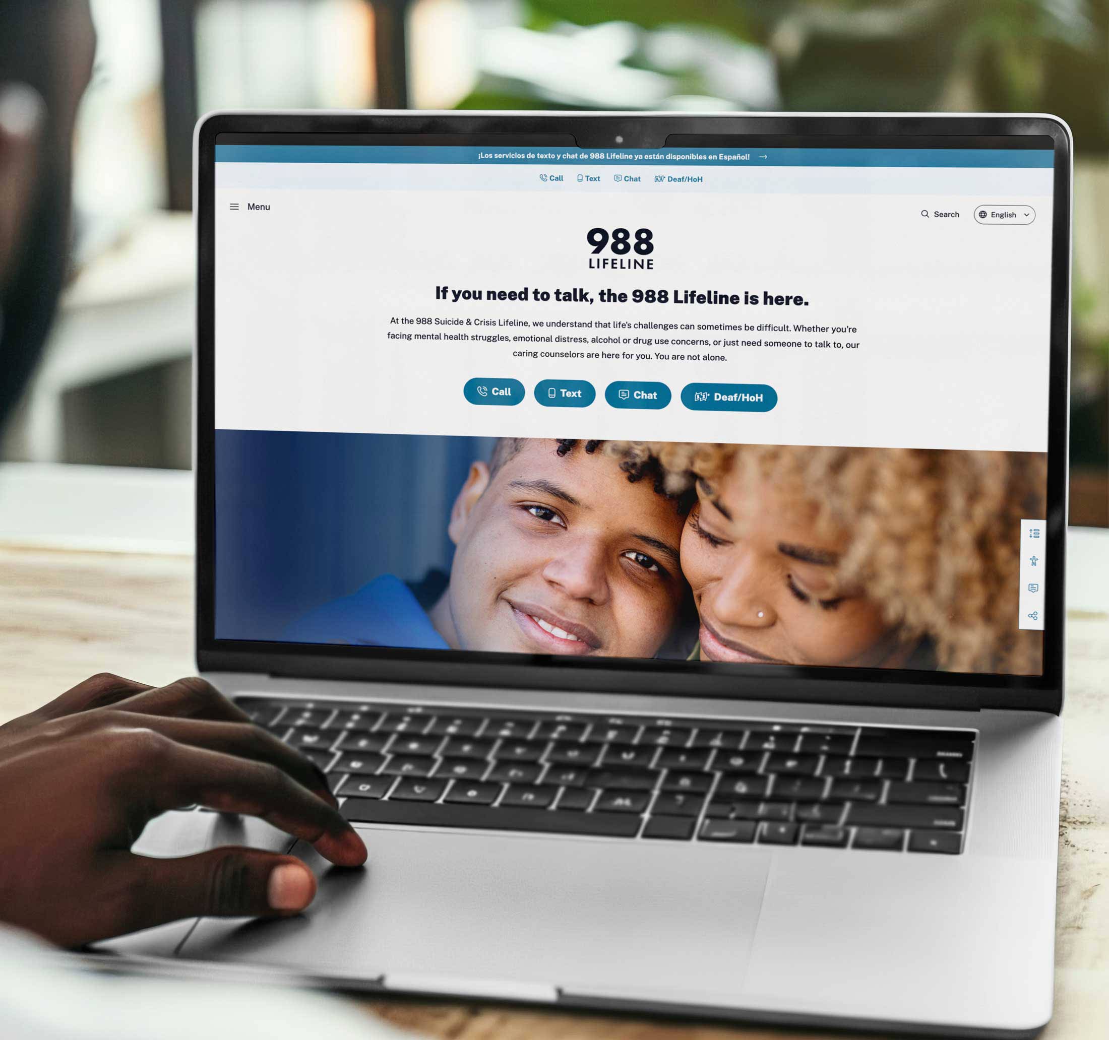 Laptop on a well-lit table featuring the 988 Lifeline homepage.