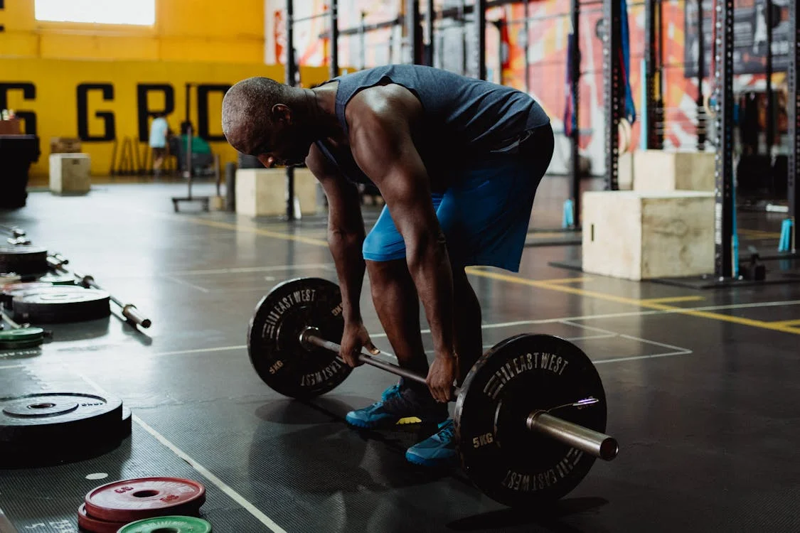 man hinging forward to pick up barbell