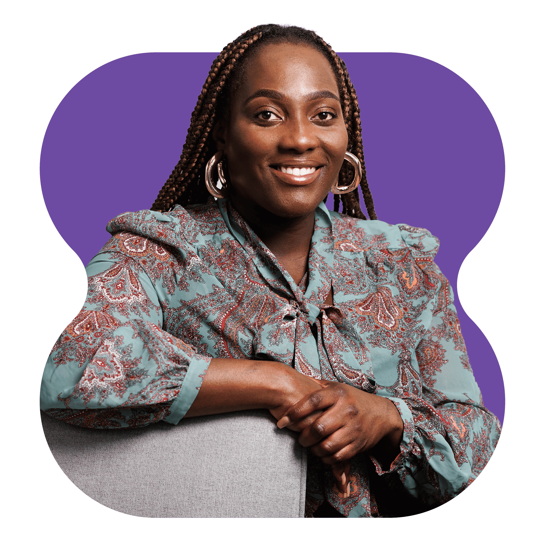 Studio portrait of person seated, wearing patterned top, against a purple background.