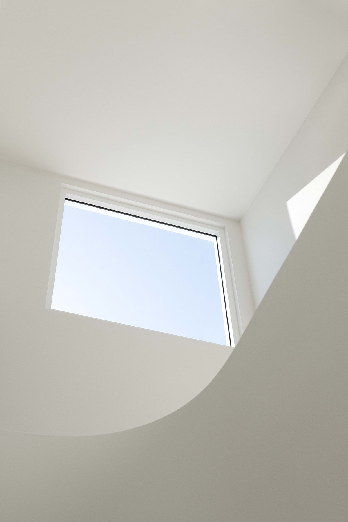 Skylight framed by sculpted ceiling geometry at The Stables, drawing daylight deep into the home.
