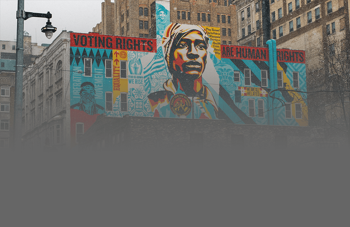 A vibrant mural featuring a stylized face against a colorful abstract background on a city street.