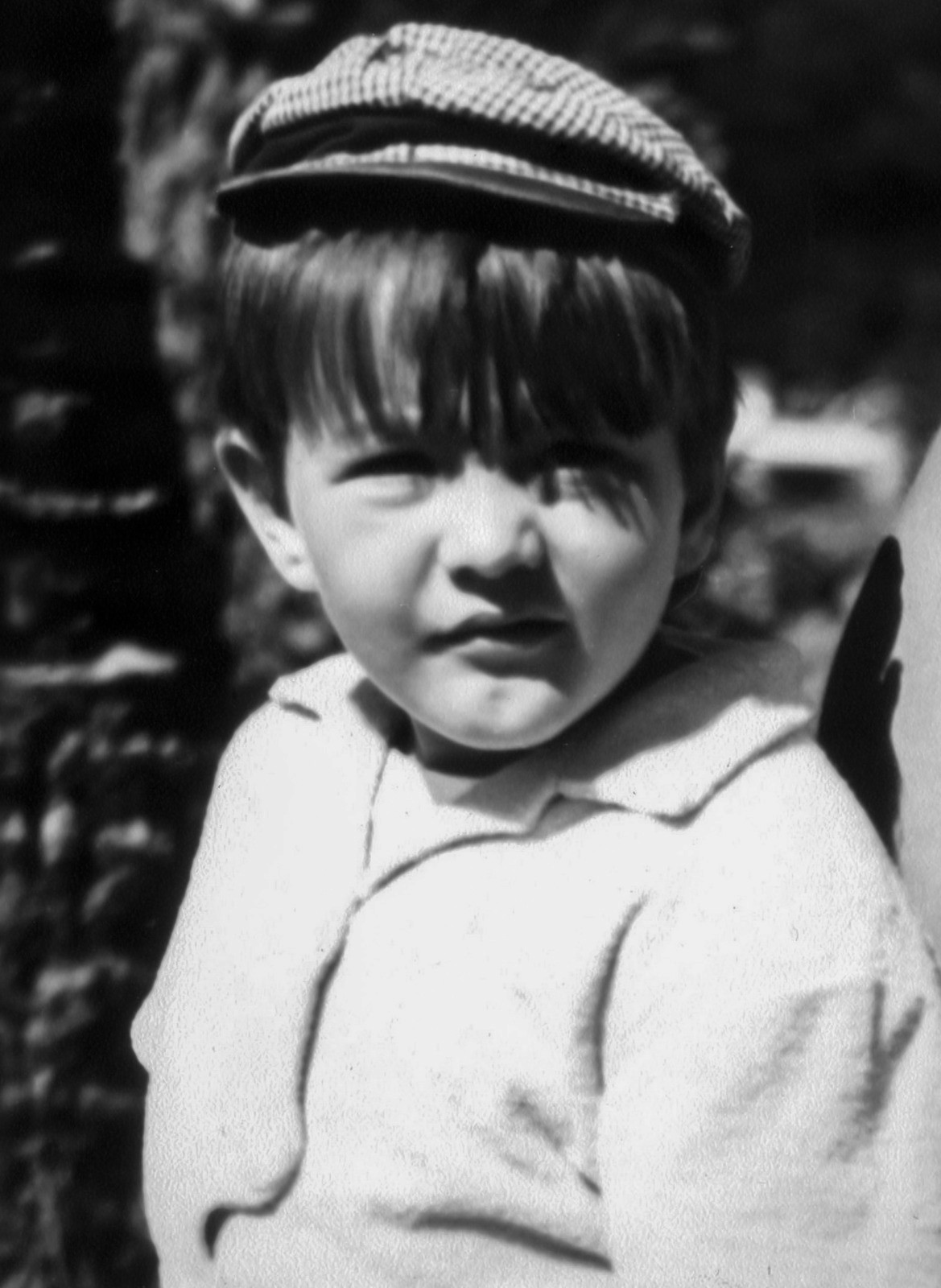 retrato blanco y negro de niño con gorra y pelo listo oscupo y camisa blanca