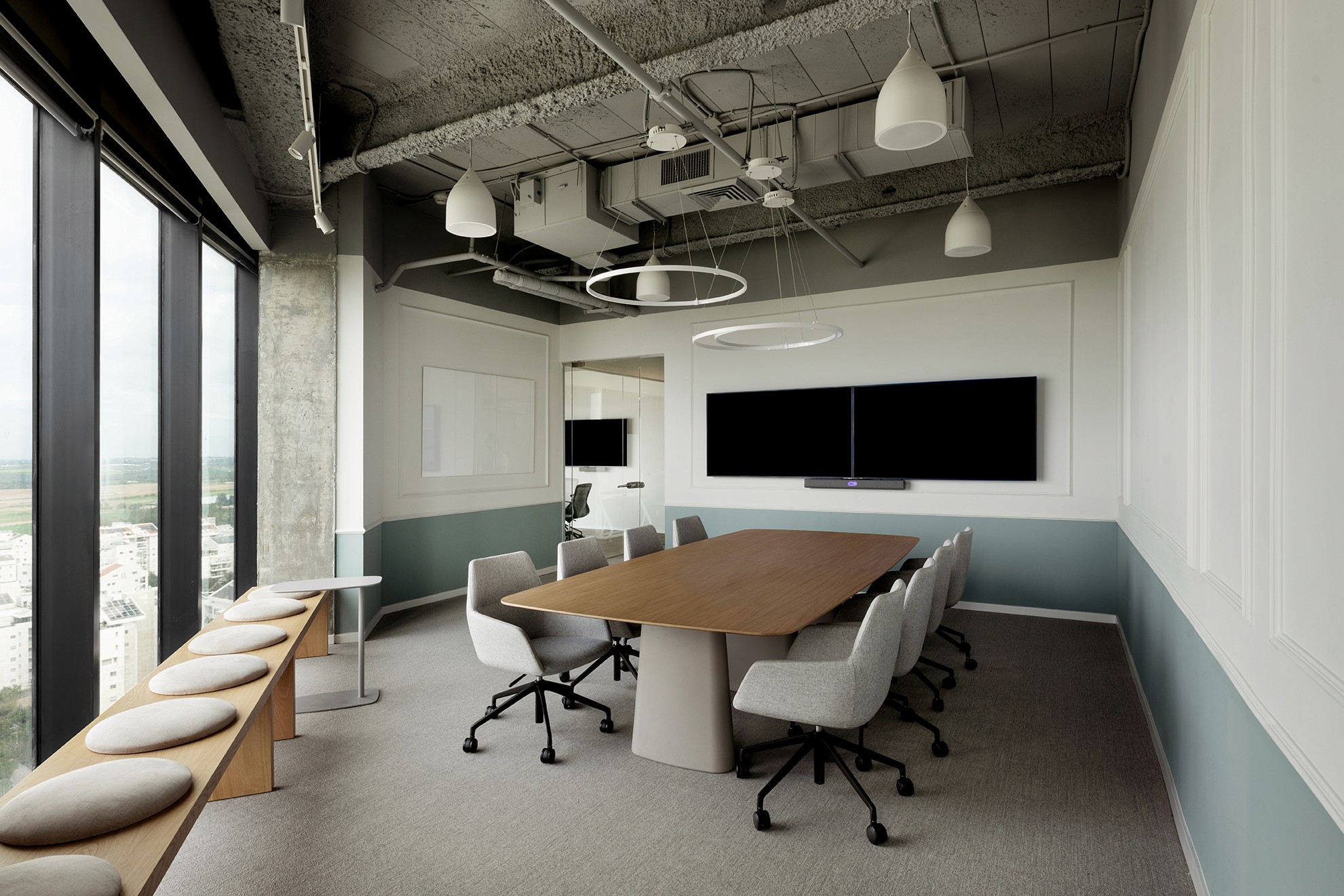 חדר ישיבות רשמי (Boardroom): שולחן מנהלים מעץ, חיפוי קיר דקורטיבי בגווני המותג ותקרה חשופה במראה תעשייתי מעודן