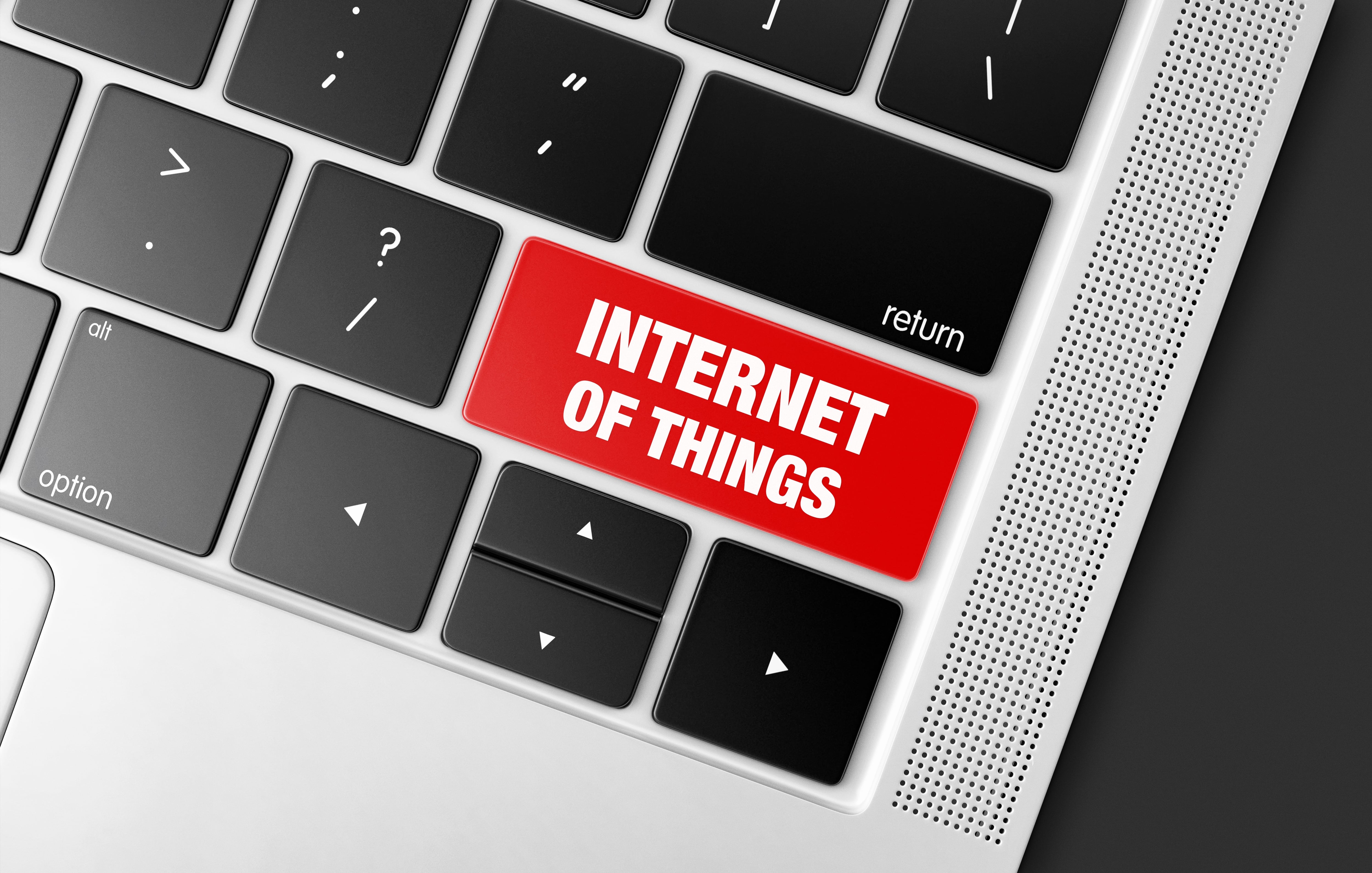 A close-up of a silver laptop keyboard with a prominent, large red key that reads 'INTERNET OF THINGS,' symbolizing connectivity and smart technology.