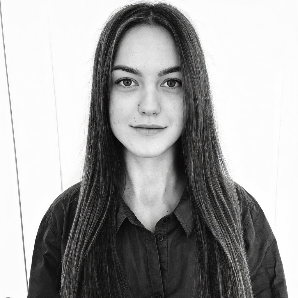 A woman with straight blonde hair wearing a light colored sweater looks away.