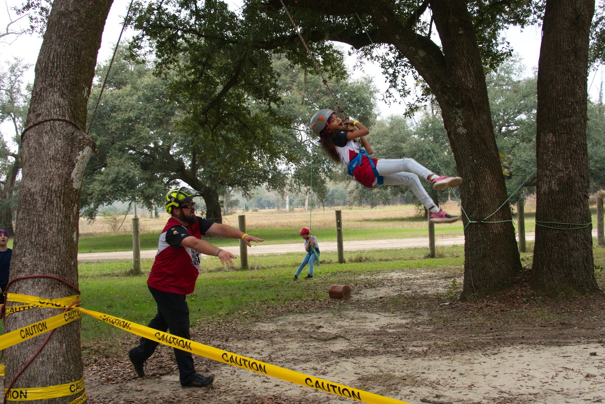 treeapalooza 2022 kids climb area child swinging in tree from harness and rope