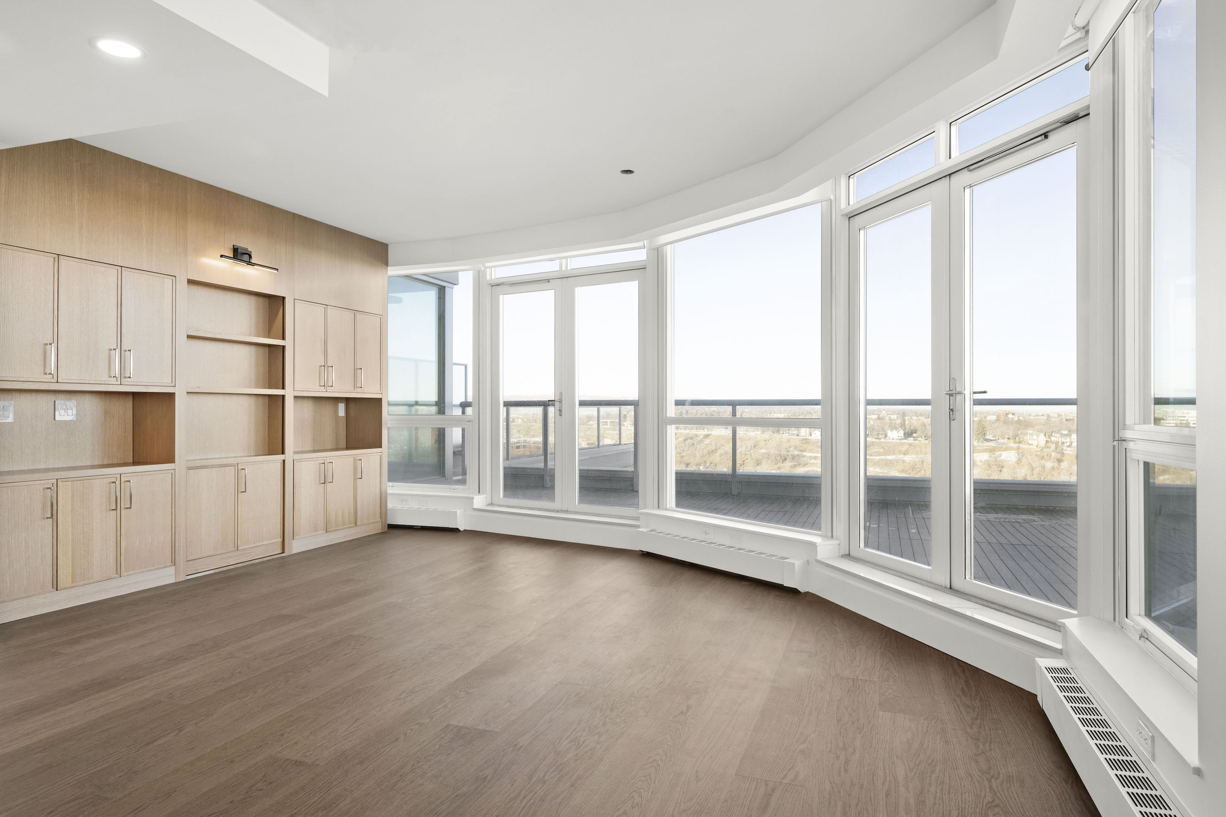 Eau Claire dining room after: oak built-in cabinetry and new wide-plank flooring along the curved windows