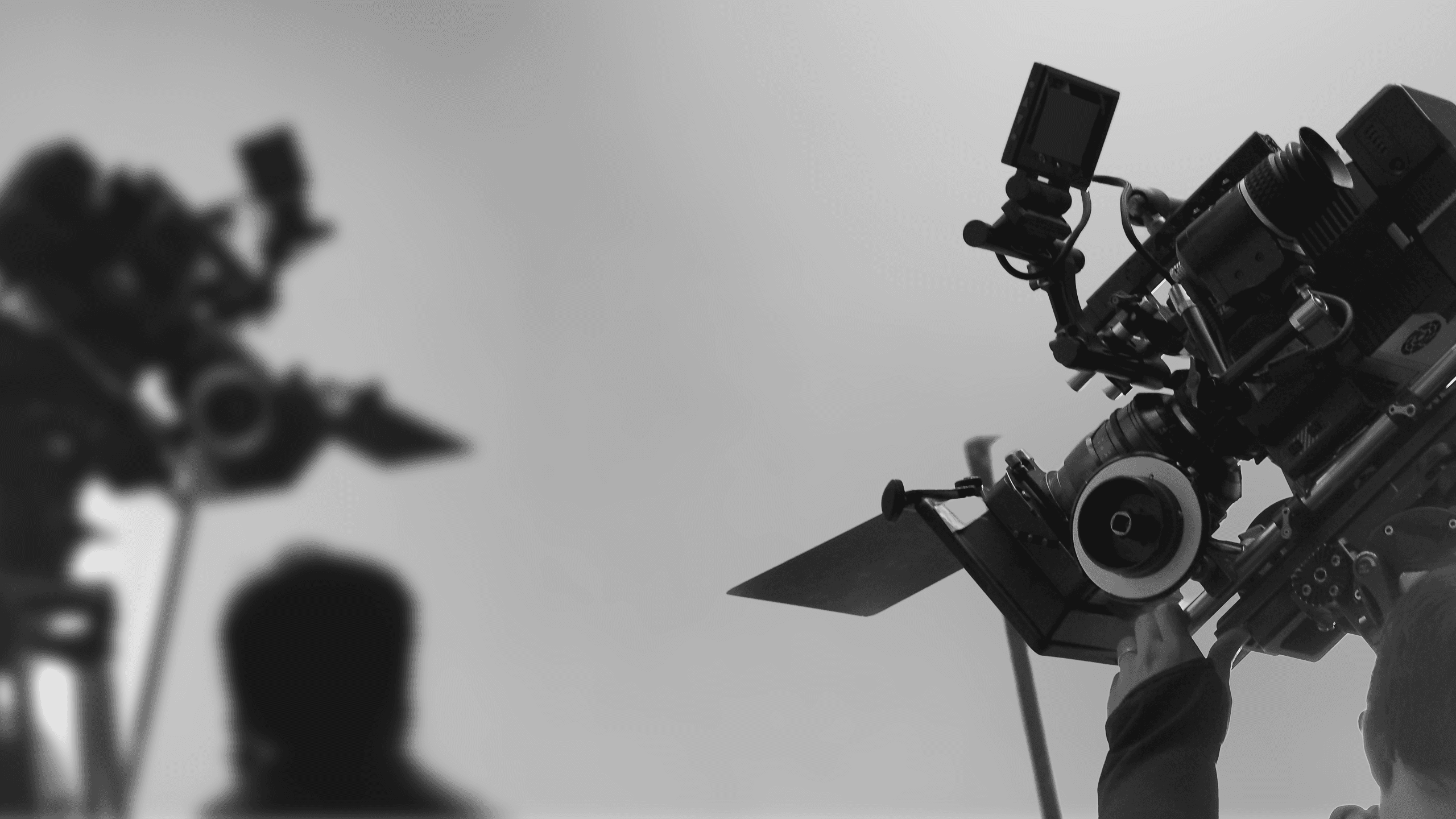Low-angle black and white shot of a professional digital cinema camera rig angled up toward an overcast sky