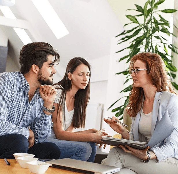 A modern hallway features vibrant teal and orange geometric and leaf patterns, with glossy tiled floors, a large rectangular light fixture, and a small shelf holding a potted plant, all leading to a large, frosted window at the end.