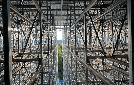 Four diverse professionals collaboratively working on a laptop, with one person pointing at the screen while others observe.