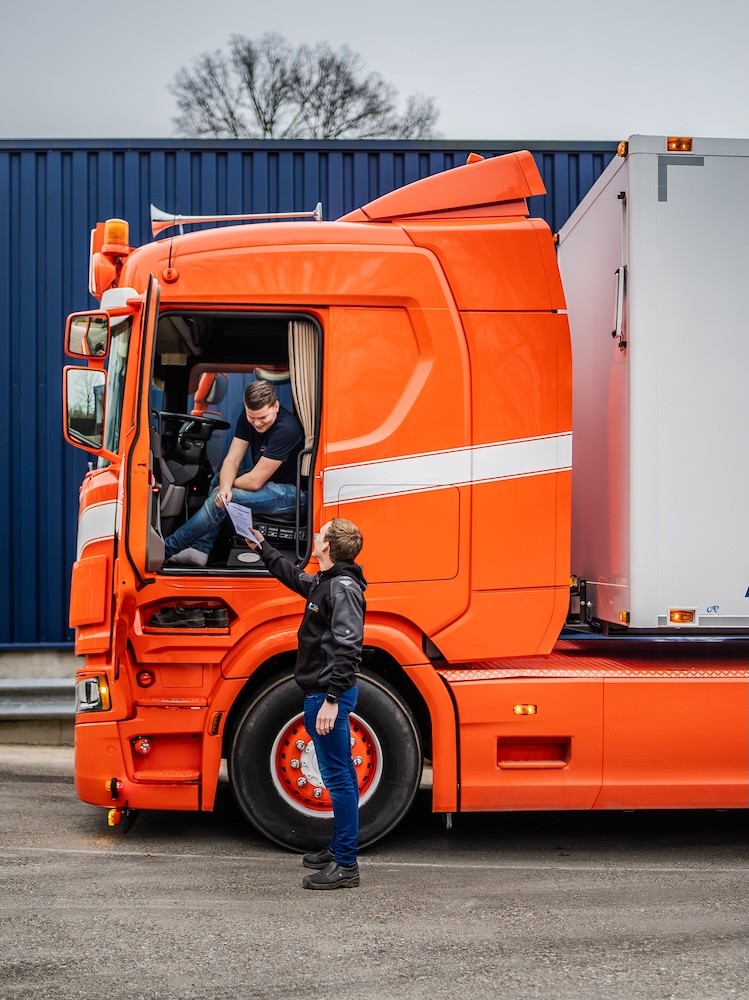 Iemand handigd een formulier over aan een vrachtwagenchauffeur.