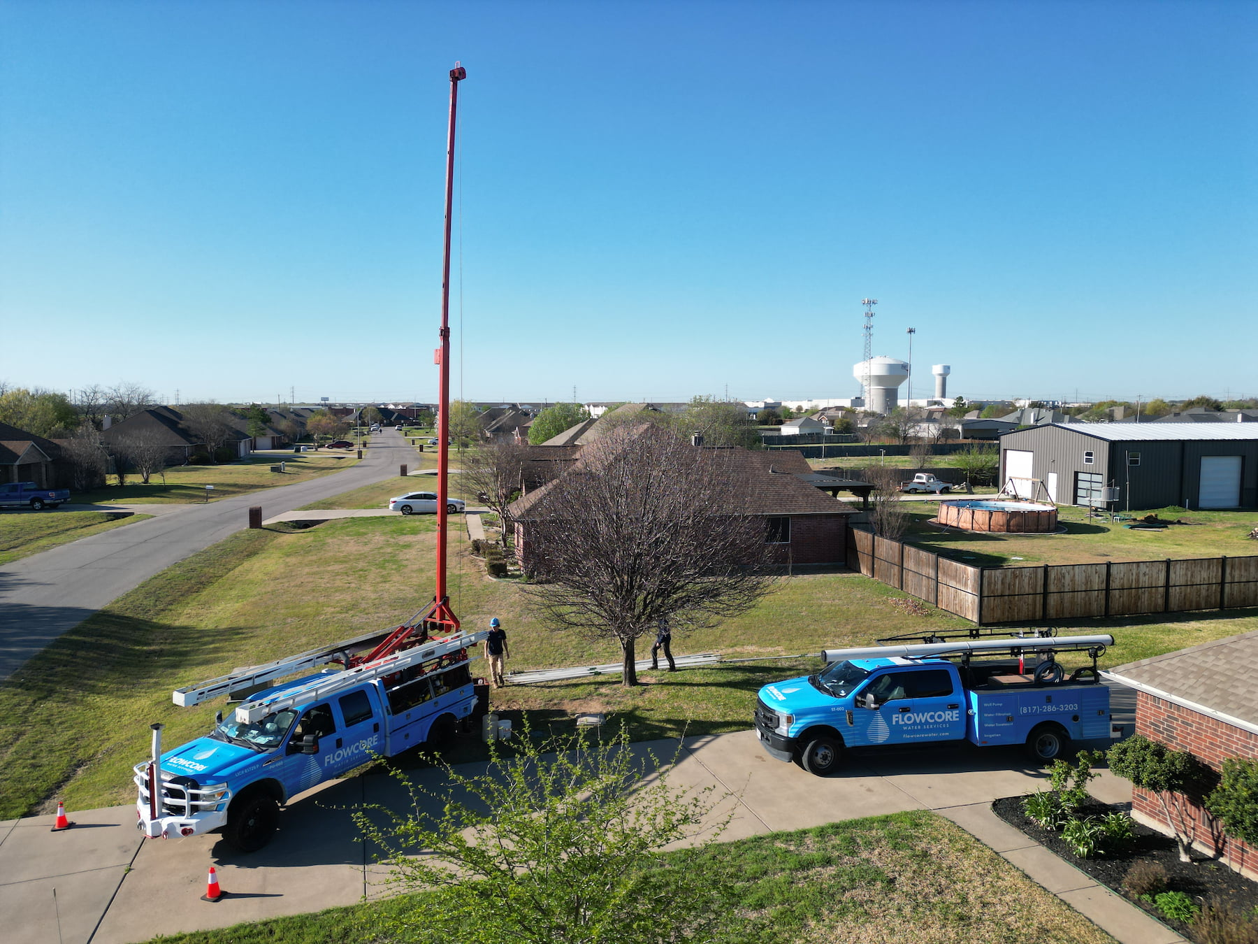 Flowcore Water Services crew drilling a residential water well in North Texas, with drill rig mast extended and service truck on site — serving DFW and North Texas
