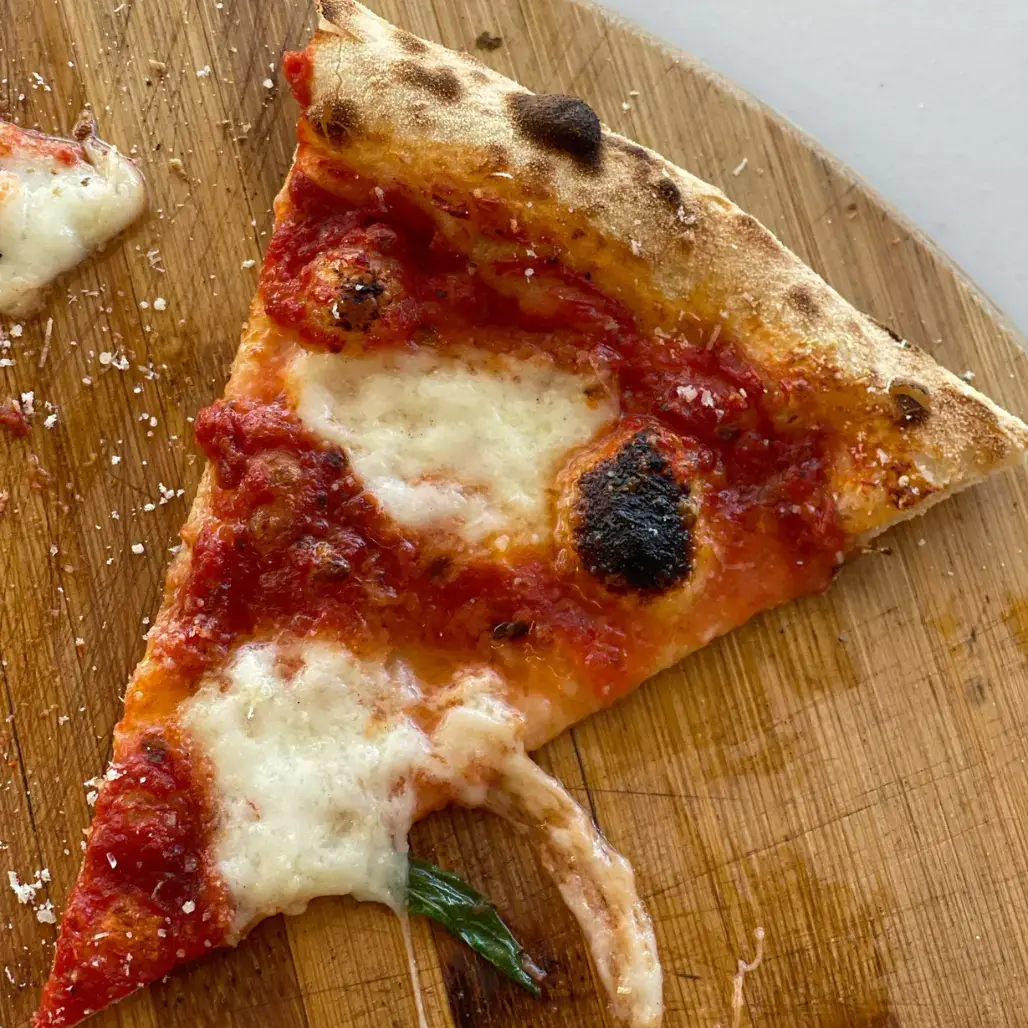 Pizzastück Margherita mit Tomatensauce und Mozzarella auf Holzbrett Pizza Dielsdorf