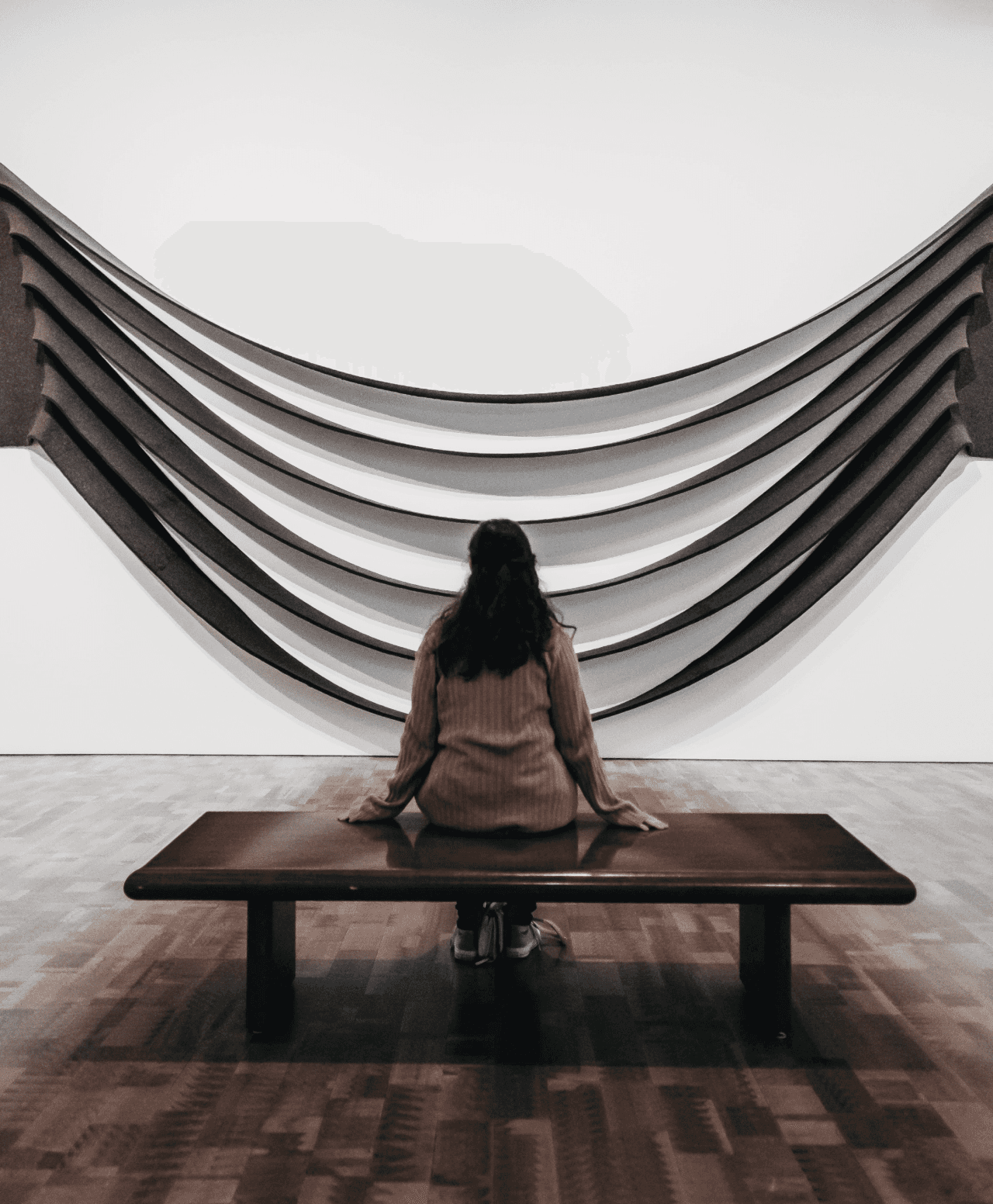 A woman sitting and looking at a work of art.