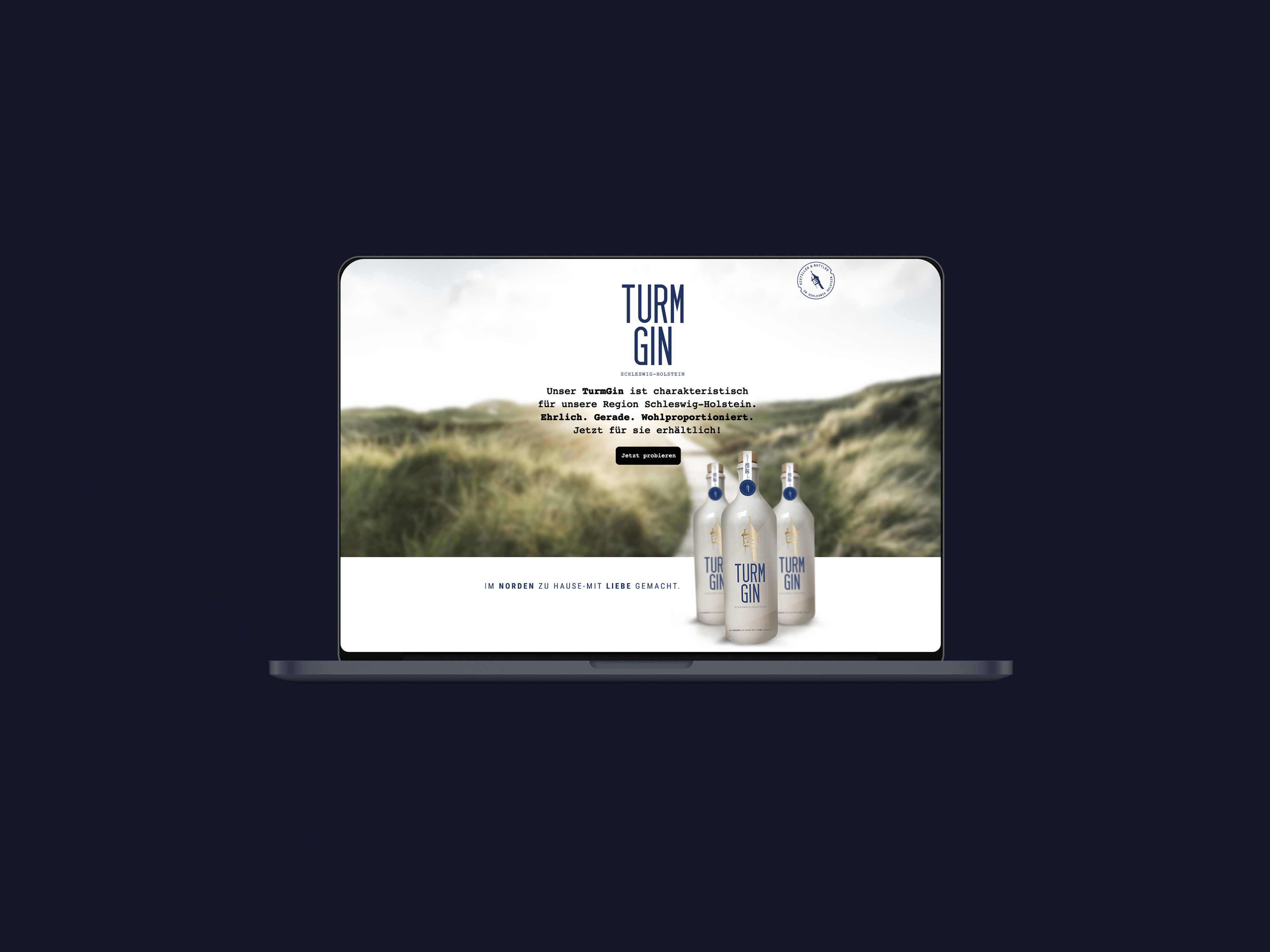 Laptop mit geöffneter Webseite, die drei Flaschen Turm Gin vor einer Dünenlandschaft zeigt