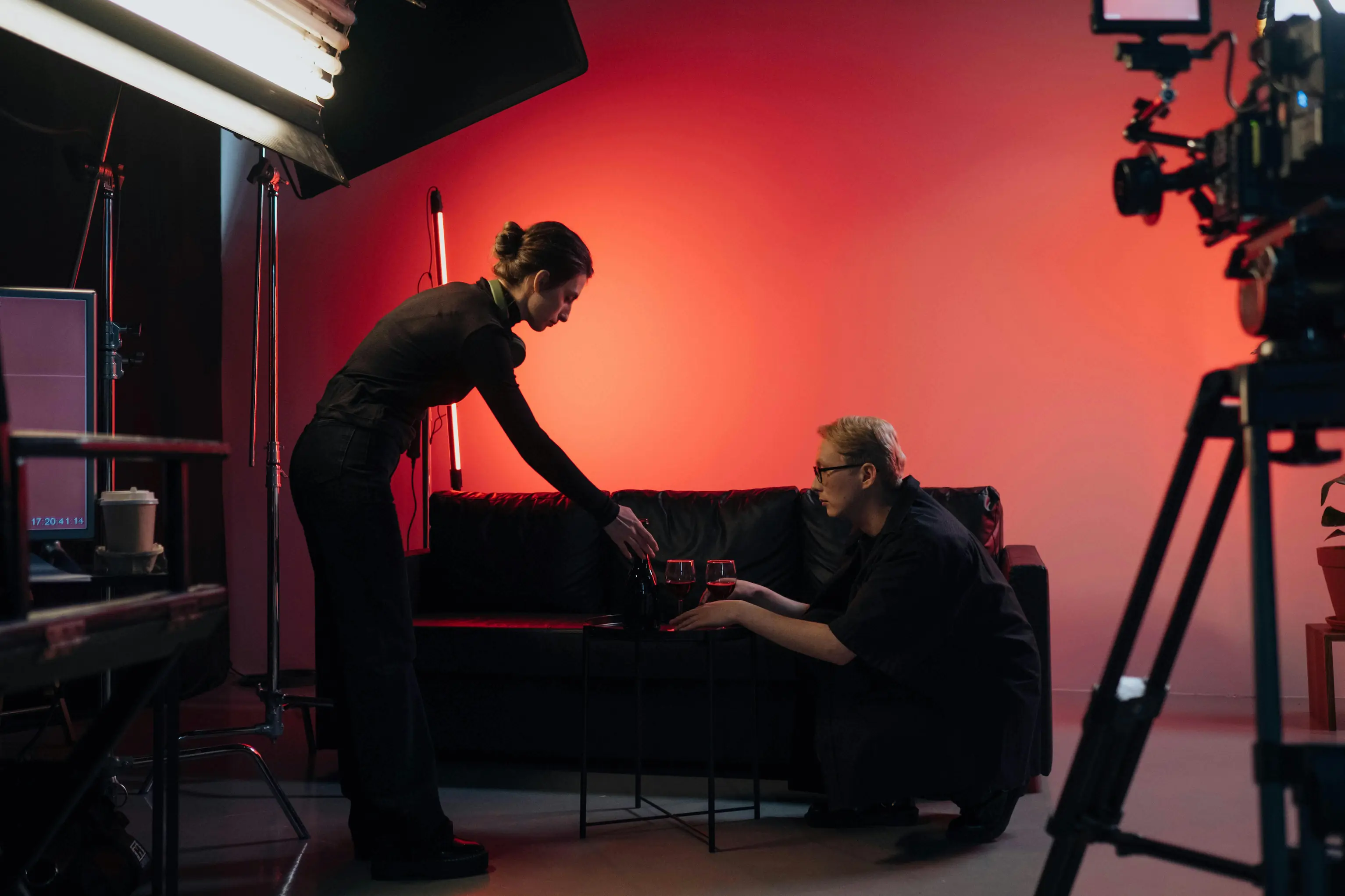 Film crew filming in a red-lit studio with cameras and production lights.