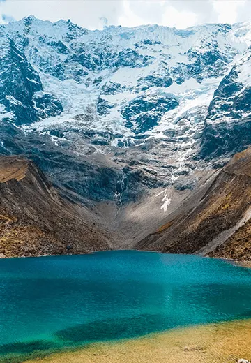 Lagoa de montanha com águas azul-turquesa aos pés de geleira e picos nevados na Cordilheira dos Andes, no Peru