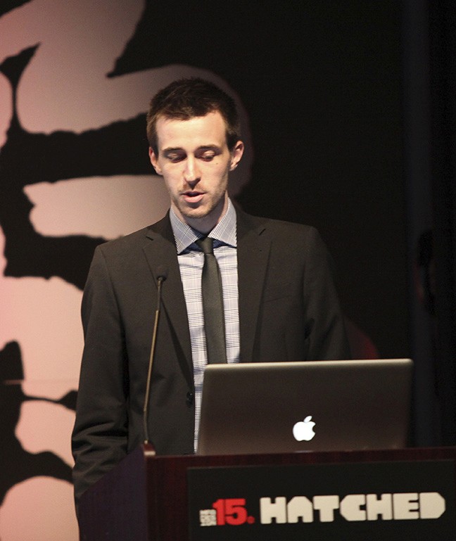 A photo of a man giving a lecture while standing at a laptop.