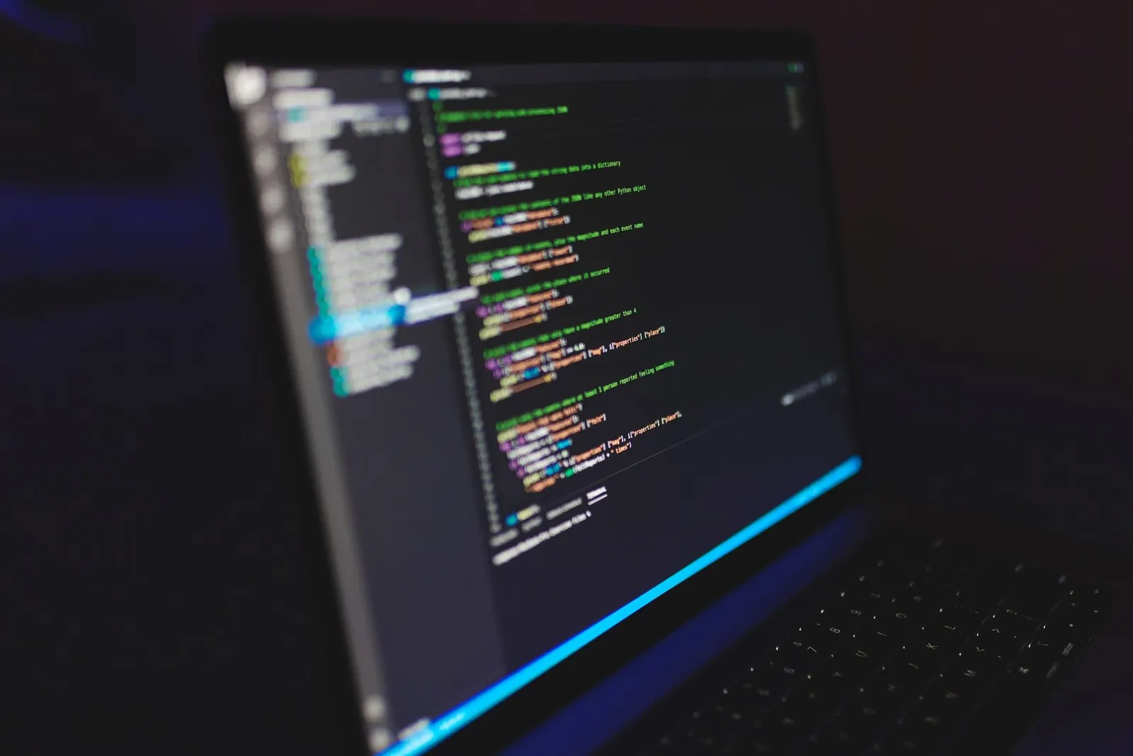 Lines of code glowing on a laptop screen in a dark room