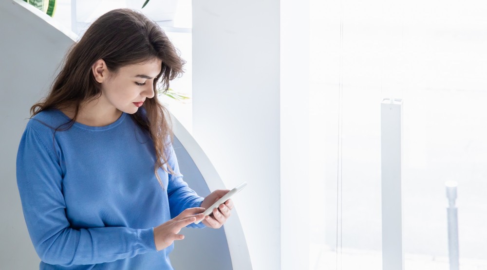 Woman in blue checking her phone with the HoustonPlus app.
