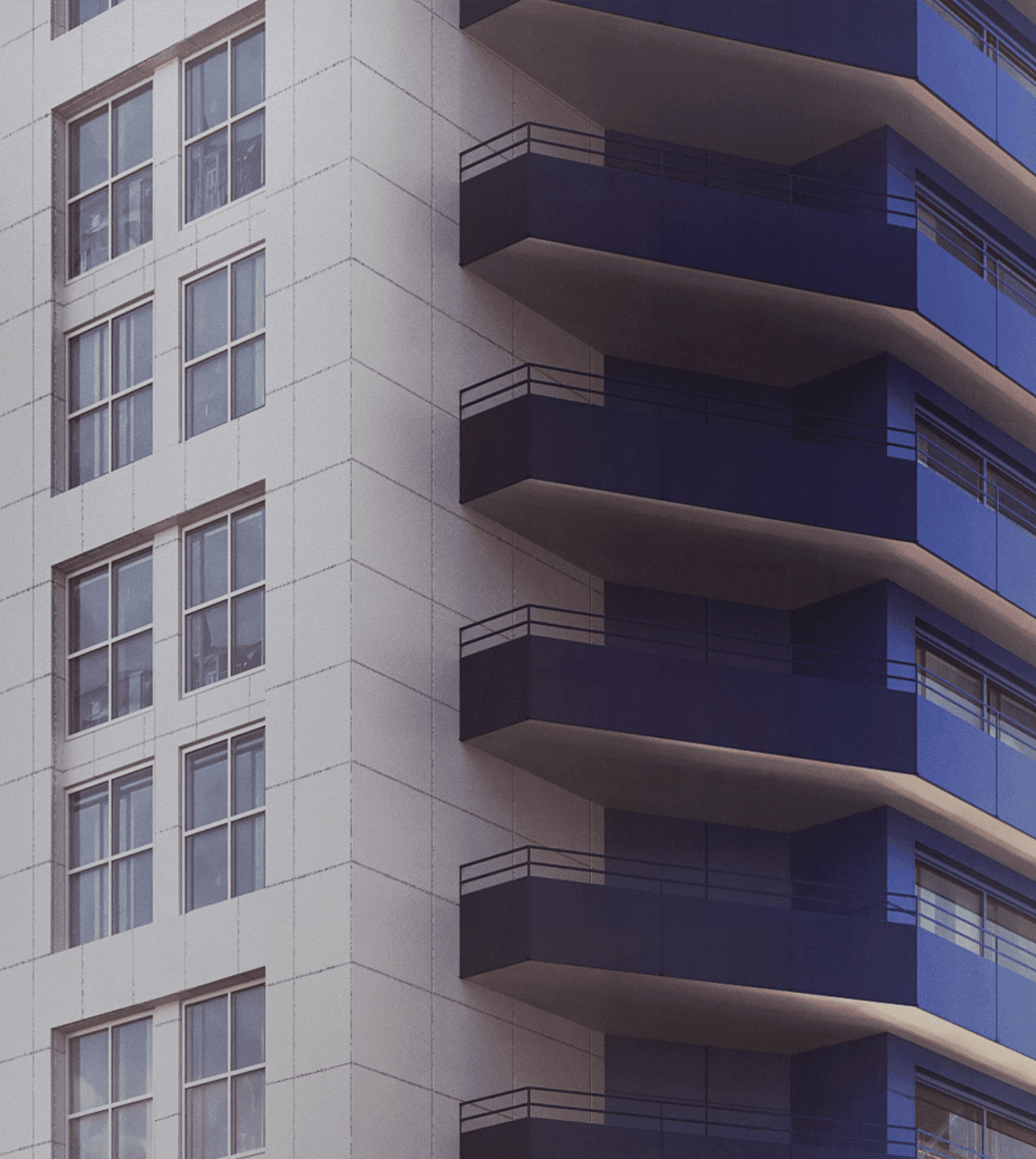 Closeup of building with windows on left side and blue balconies on the right side