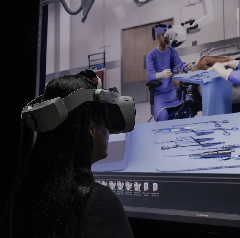 Person wearing a Varjo XR-4 mixed reality headset while viewing a surgical training simulation on a large screen