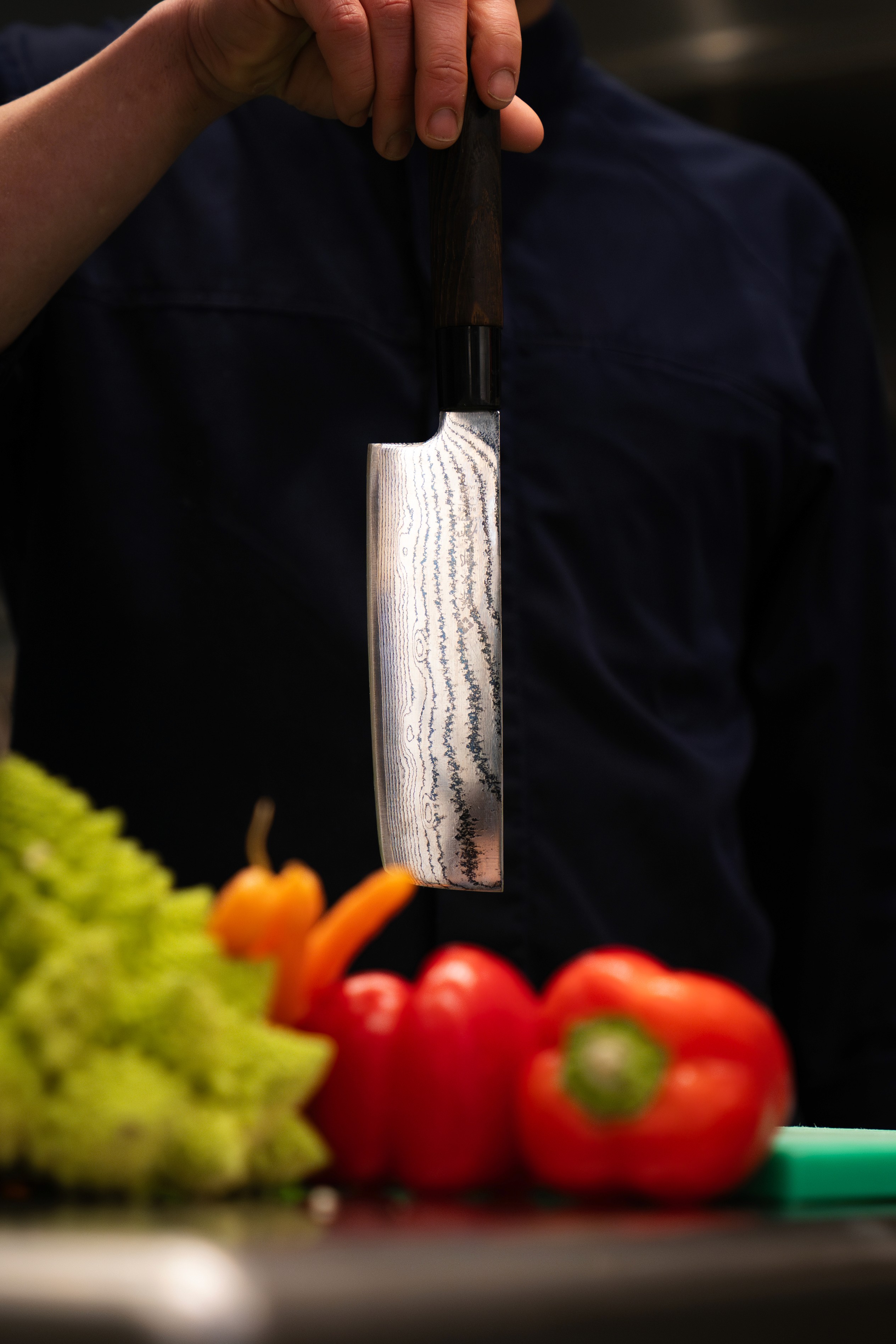 Private chef houdt een damascusmes vast bij verse groenten — Noury Chez Vous