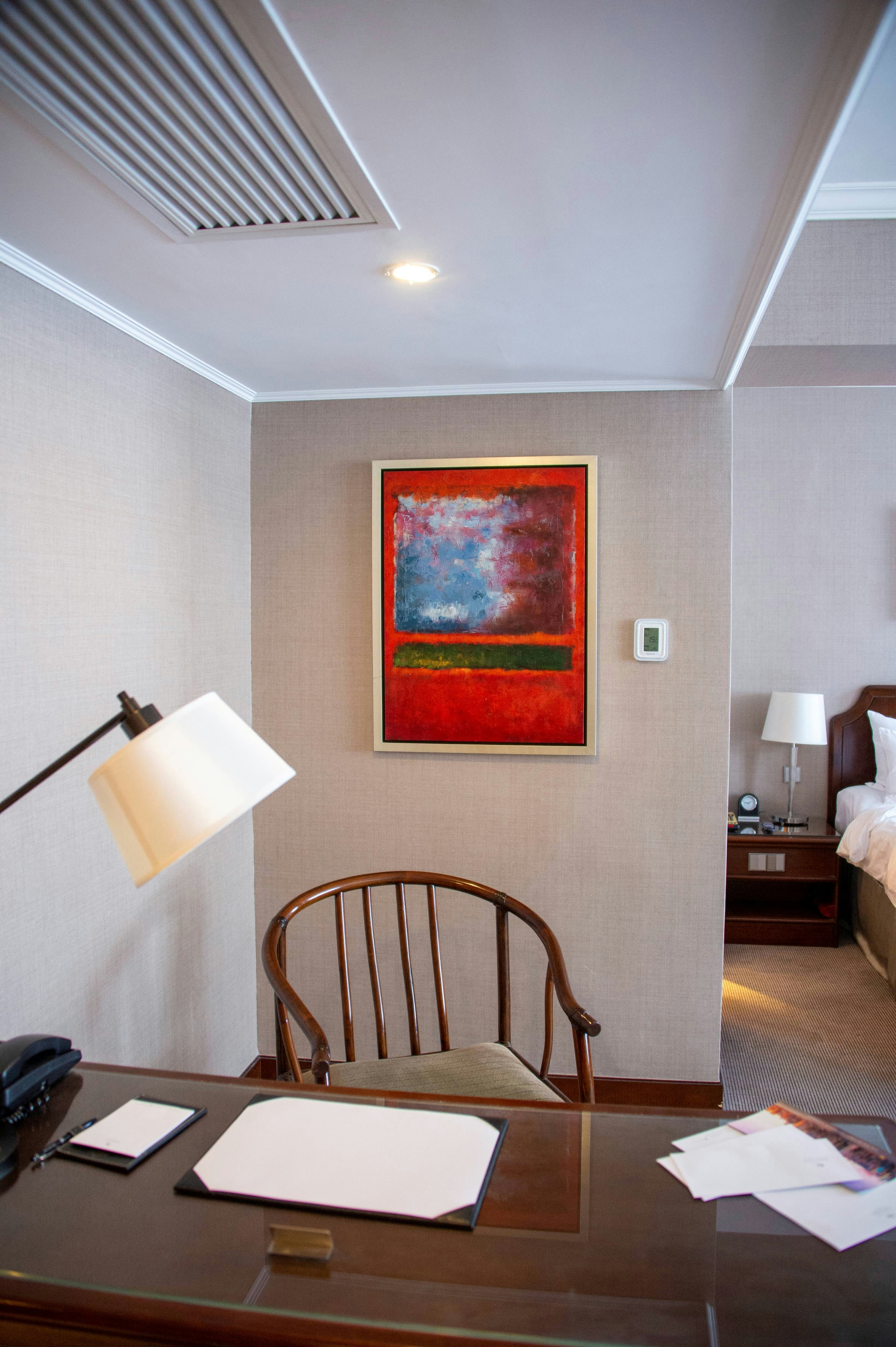a room with a table and a chair with a painting on the wall