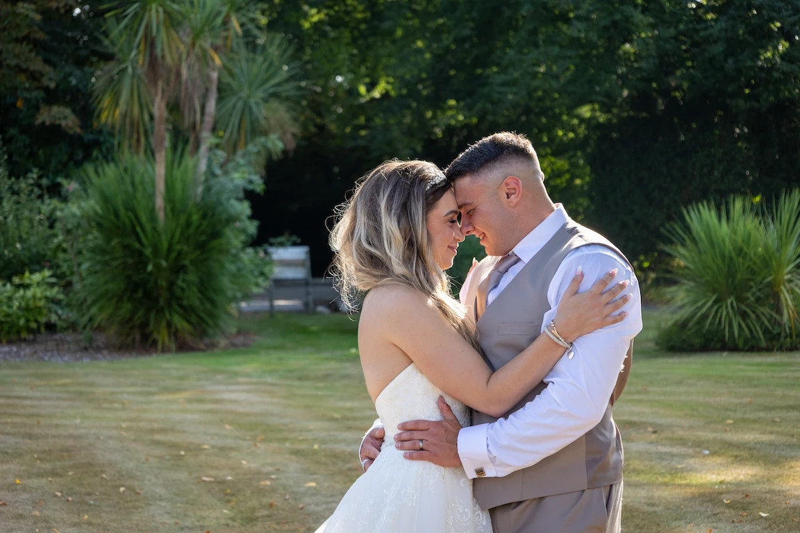 Lauren and Ethan sharing a kiss in front of Highfield Hall surrounded by gardens