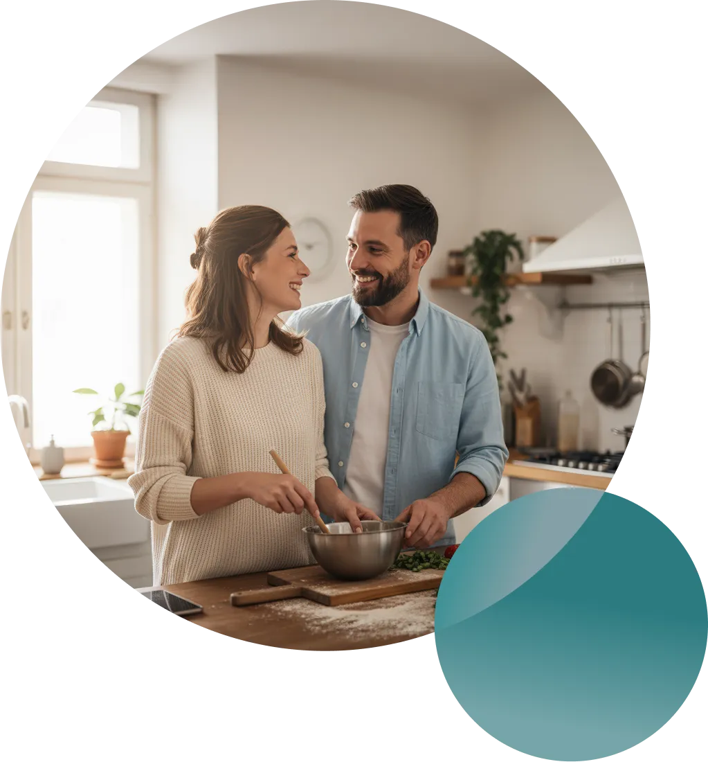 Couple cooking together in a bright kitchen while smiling at each other.