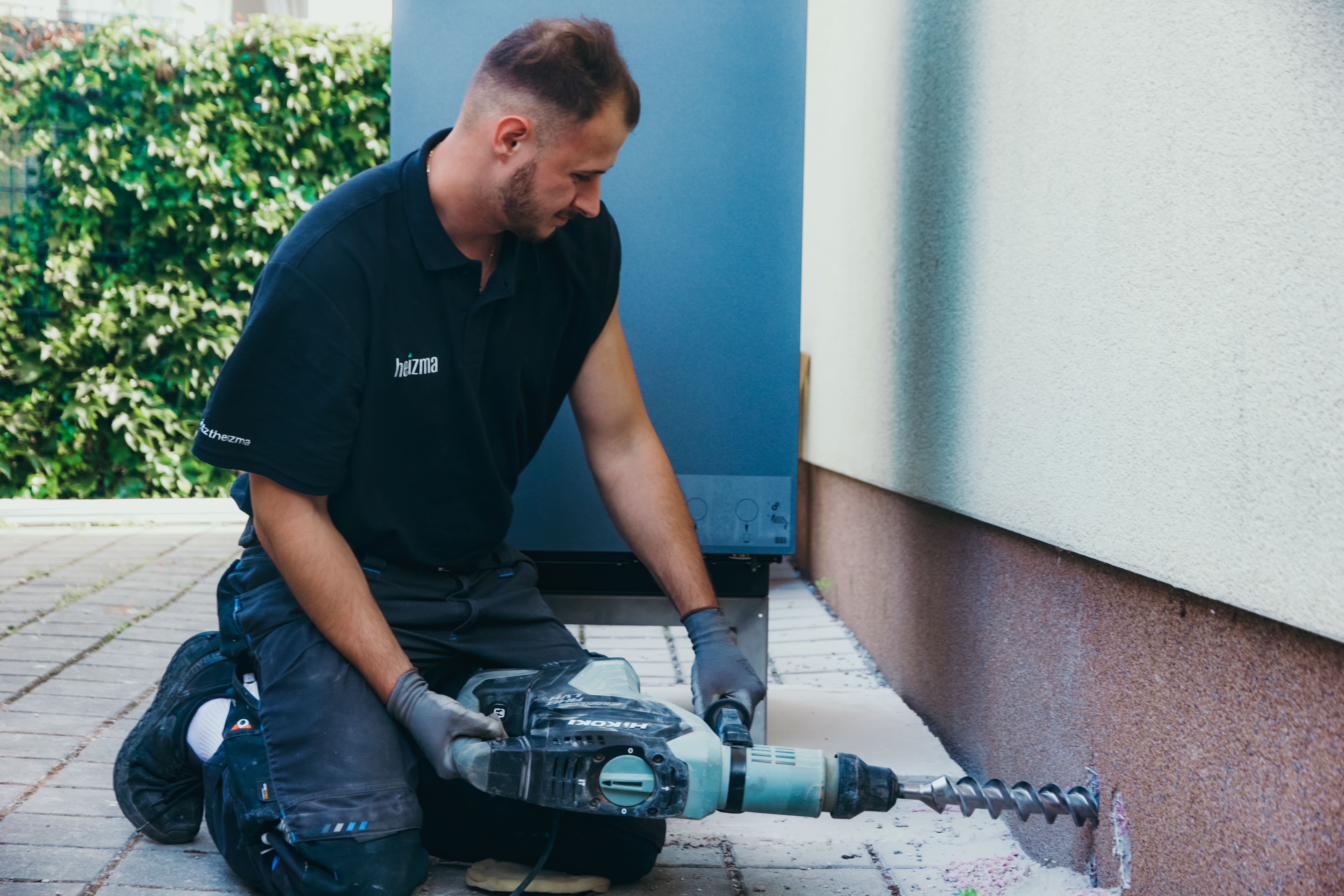 Heizma-Mitarbeiter bei der Installation bohrt ein Loch in die Hauswand