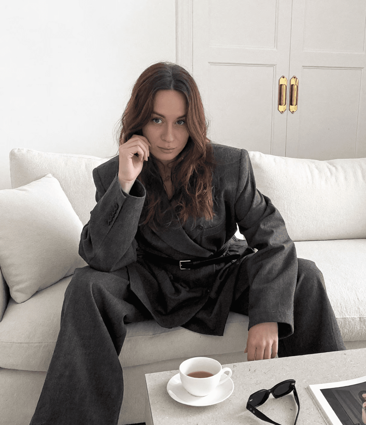 A stylish individual in a black shirt and silver pants stands against a blurred background, creating a dynamic and modern aesthetic.