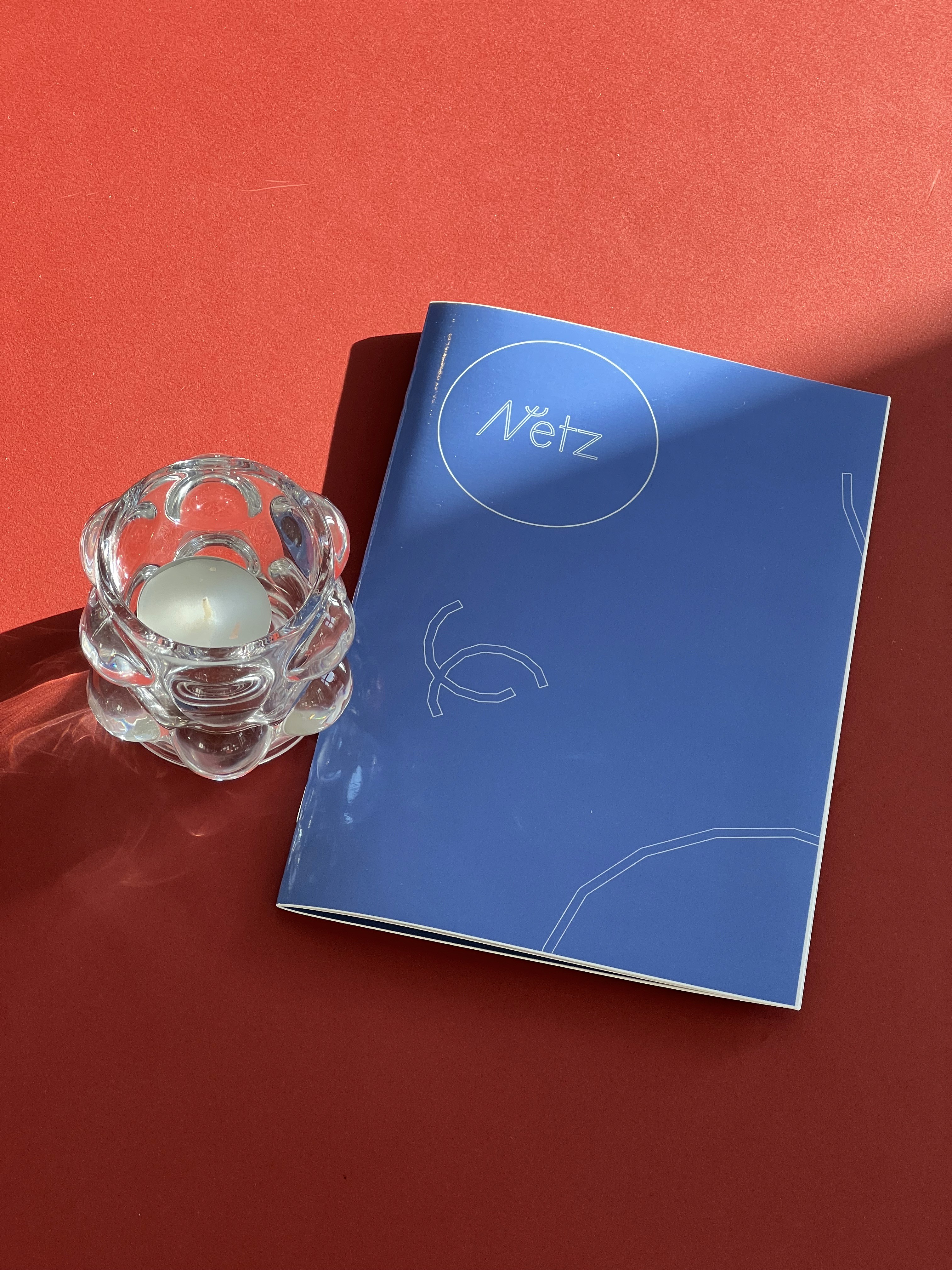 Blue Menu Booklet on red background with a transparent candleholder