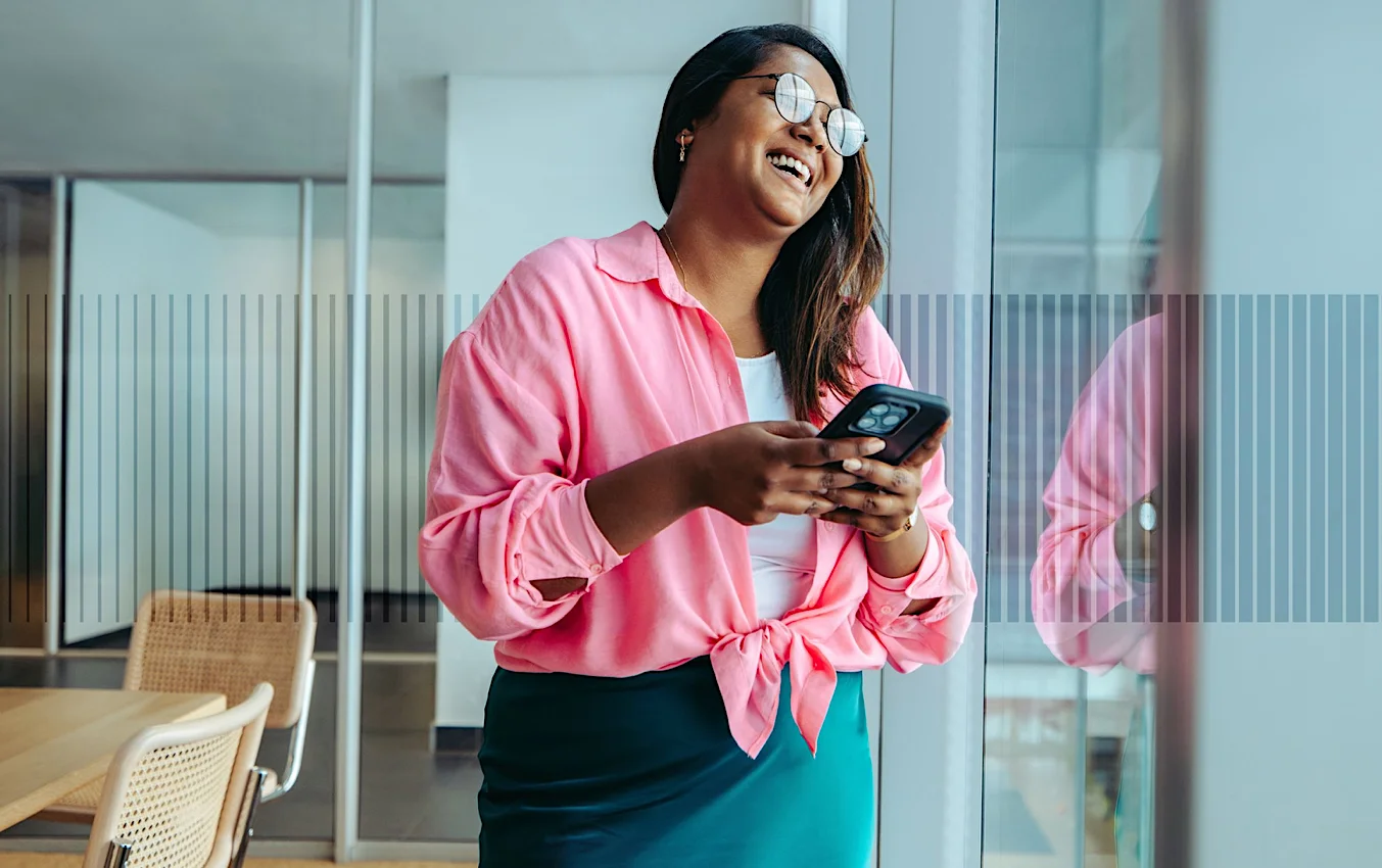 Legal professional smiling while holding a mobile phone in a modern office, representing an approachable and people-focused legal environment.